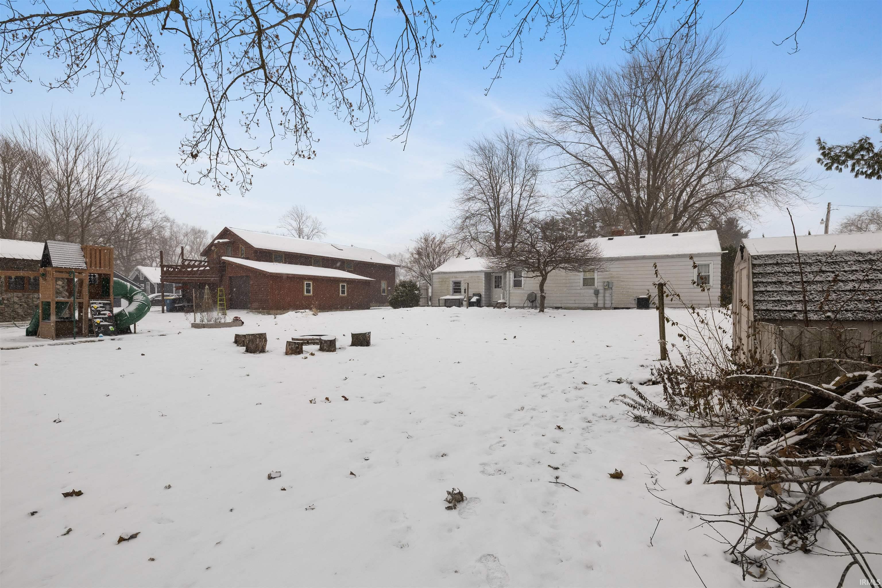 Yard layered in snow featuring a playground