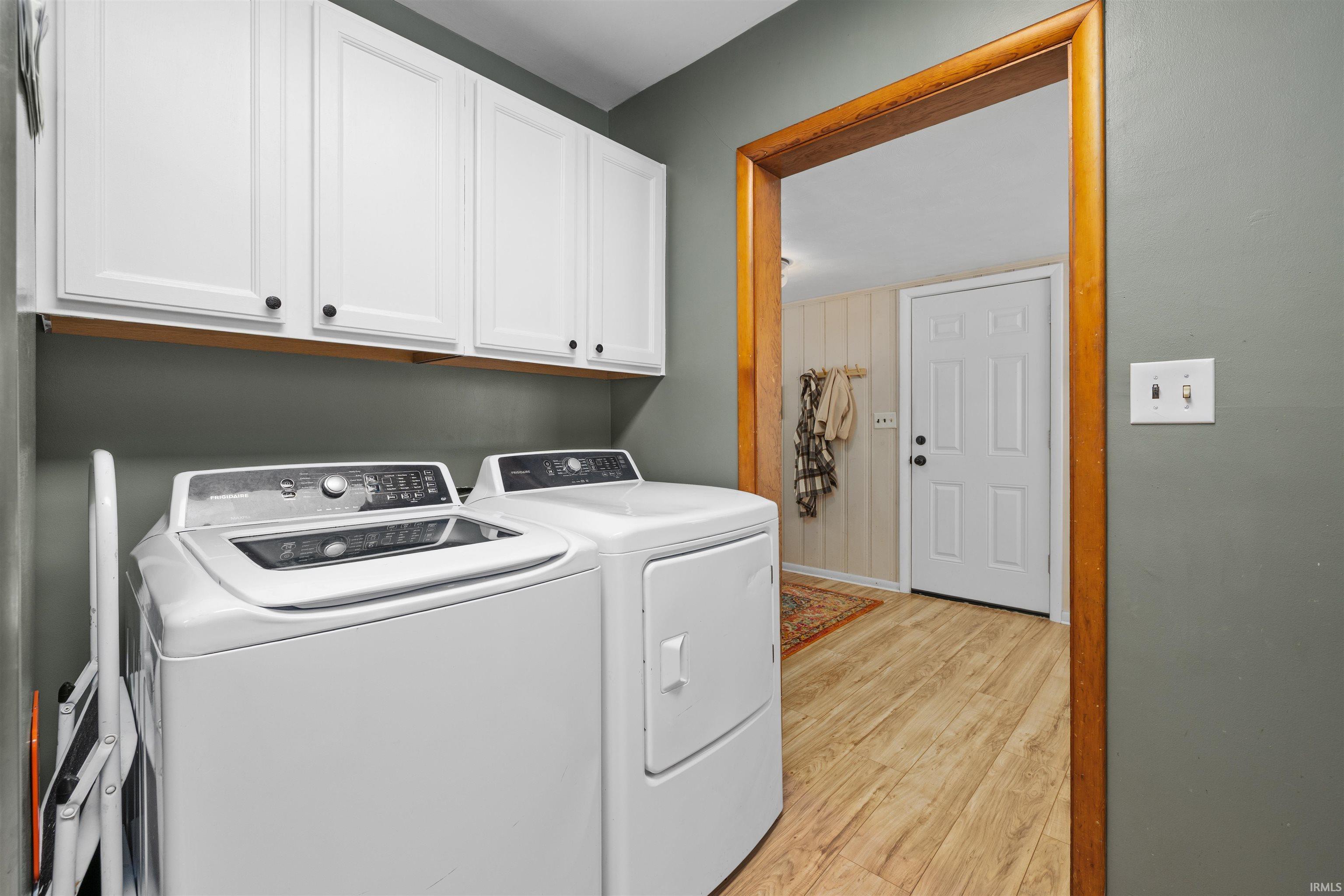 Laundry area featuring cabinet space, washer and clothes dryer, and light wood-type flooring