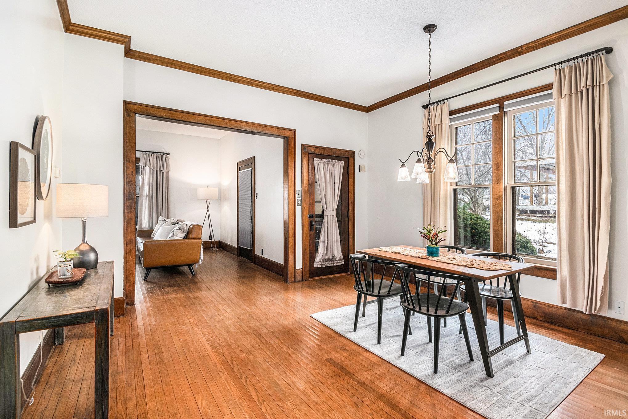 Dining area with ornamental molding, a chandelier, and hardwood / wood-style floors