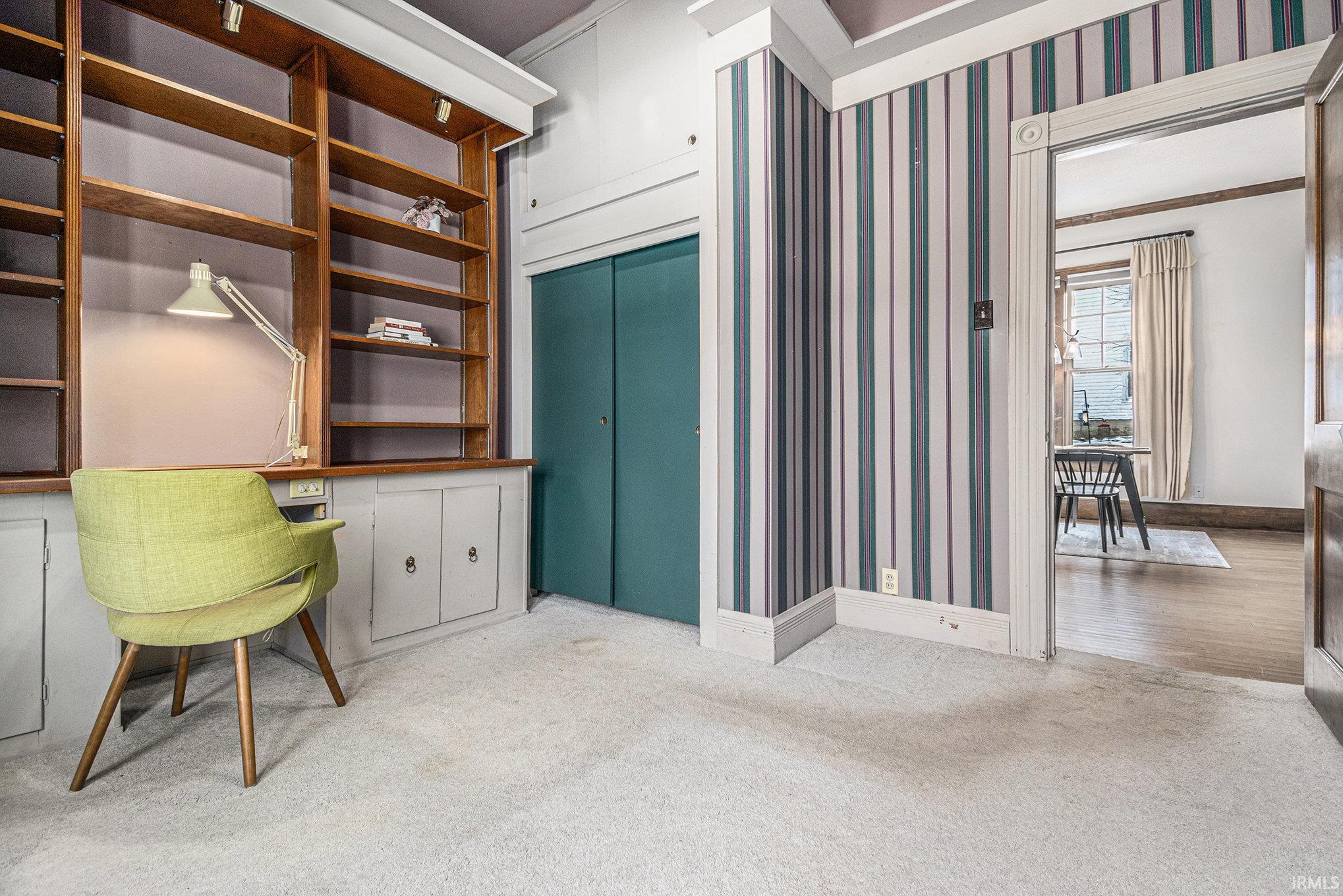 Carpeted home office featuring wallpapered walls, built in study area, and crown molding