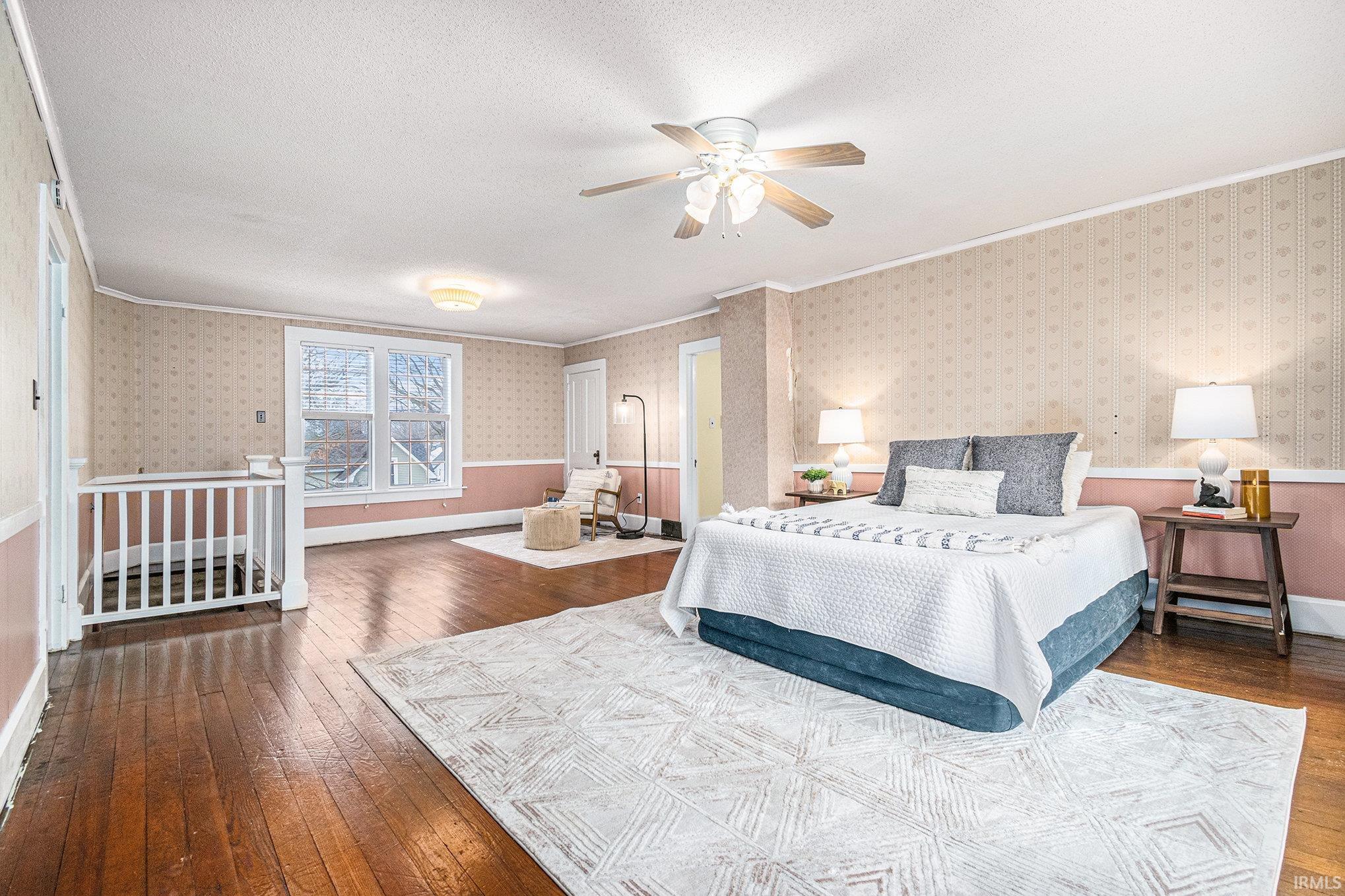 Bedroom featuring dark wood-style flooring, ceiling fan, wallpapered walls, and a textured ceiling