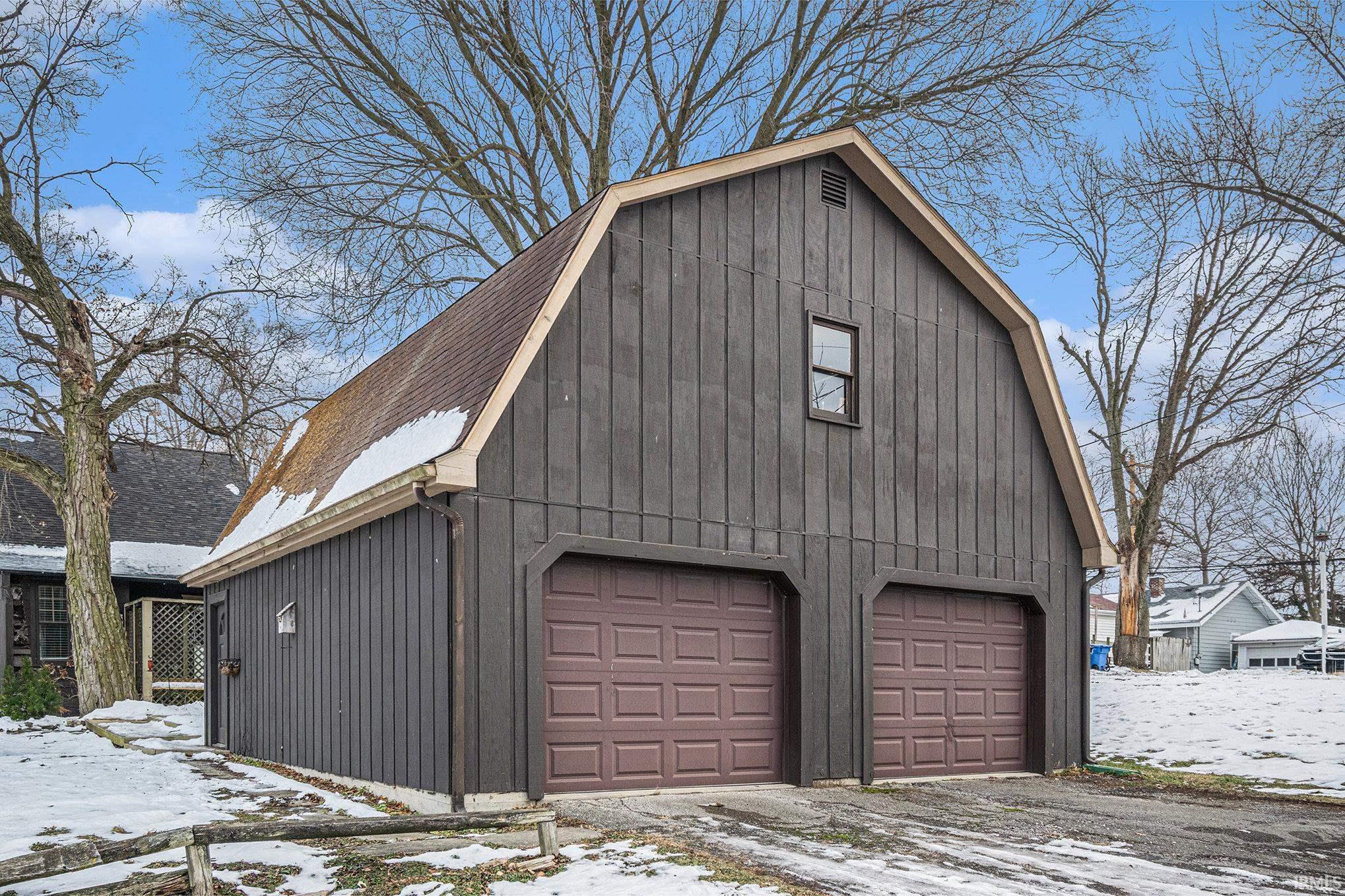 Snow covered garage featuring a detached garage