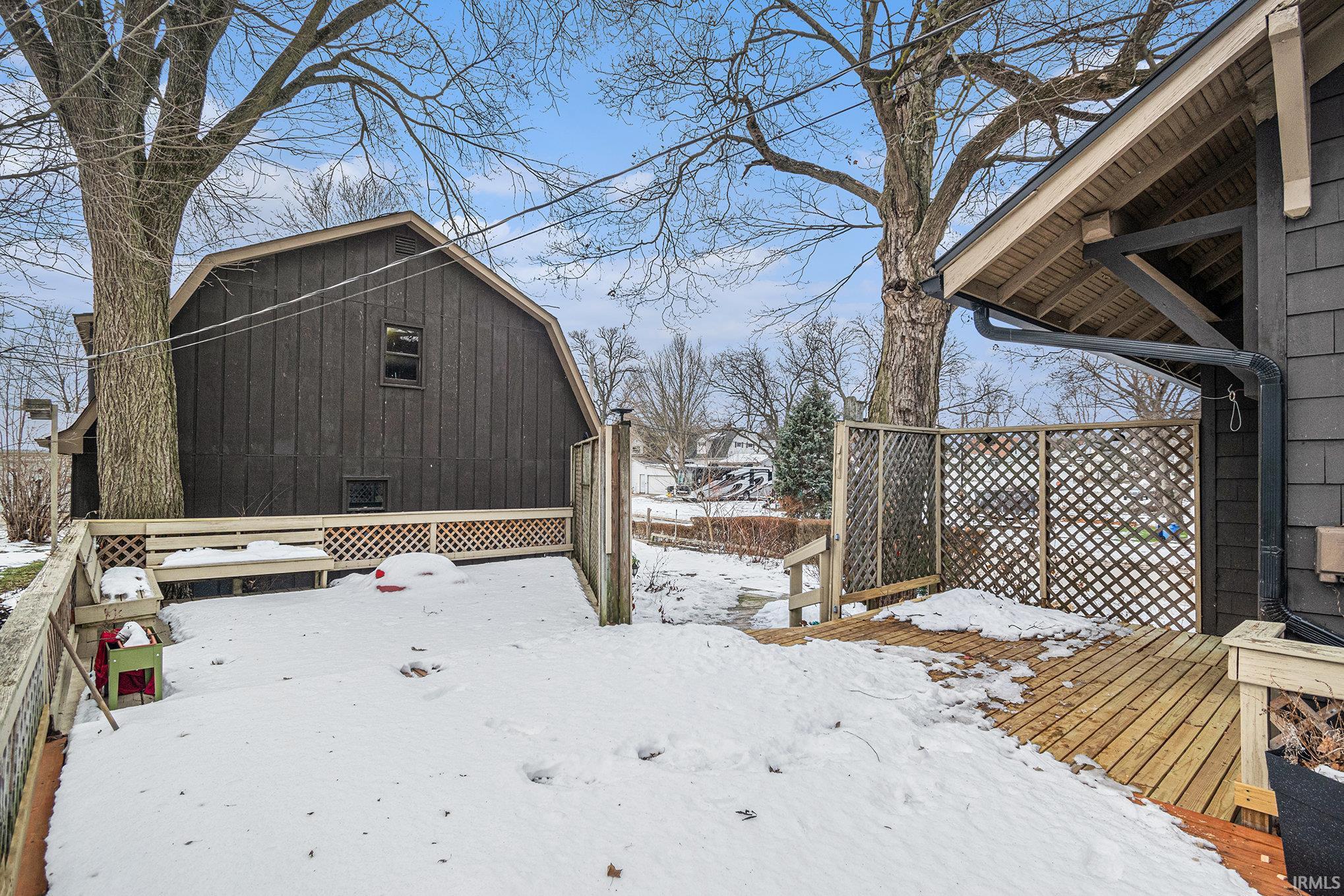 Yard layered in snow featuring a wooden deck