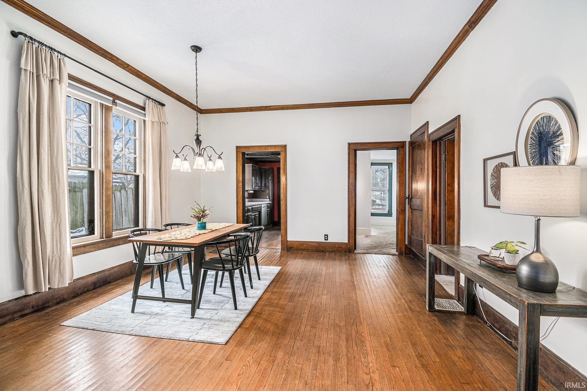 Dining area with crown molding, a chandelier, and hardwood / wood-style flooring