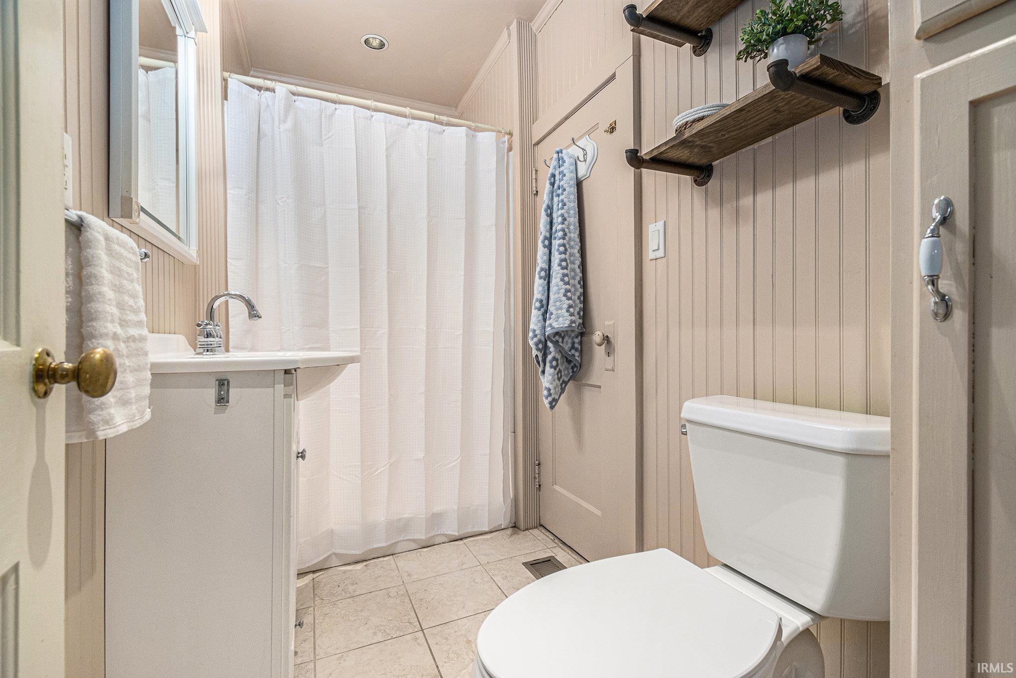 Bathroom featuring curtained shower, ornamental molding, and light tile patterned flooring