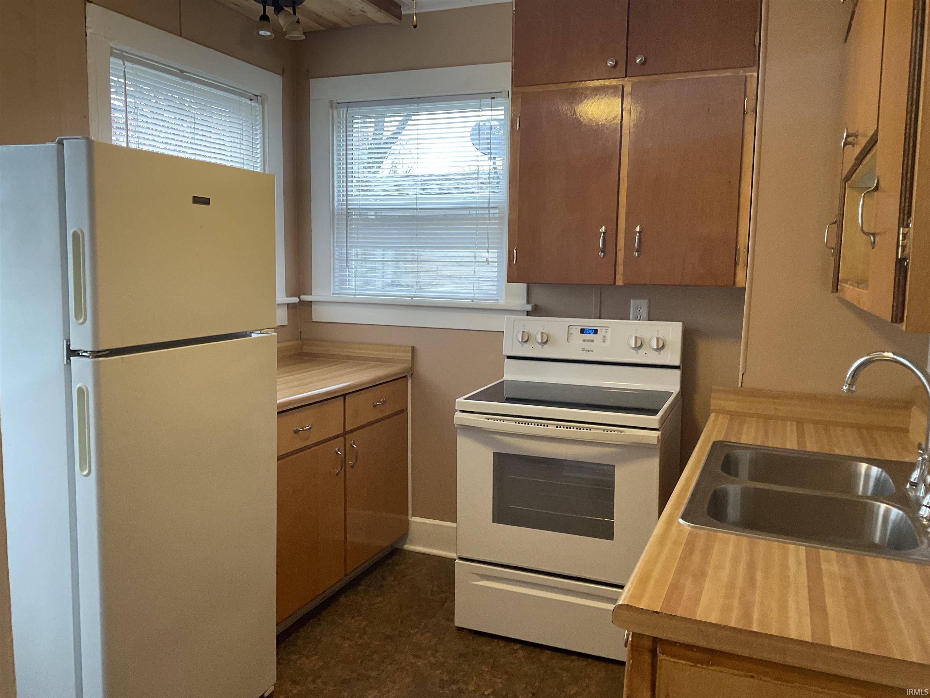 Kitchen with white appliances, light countertops, and brown cabinetry