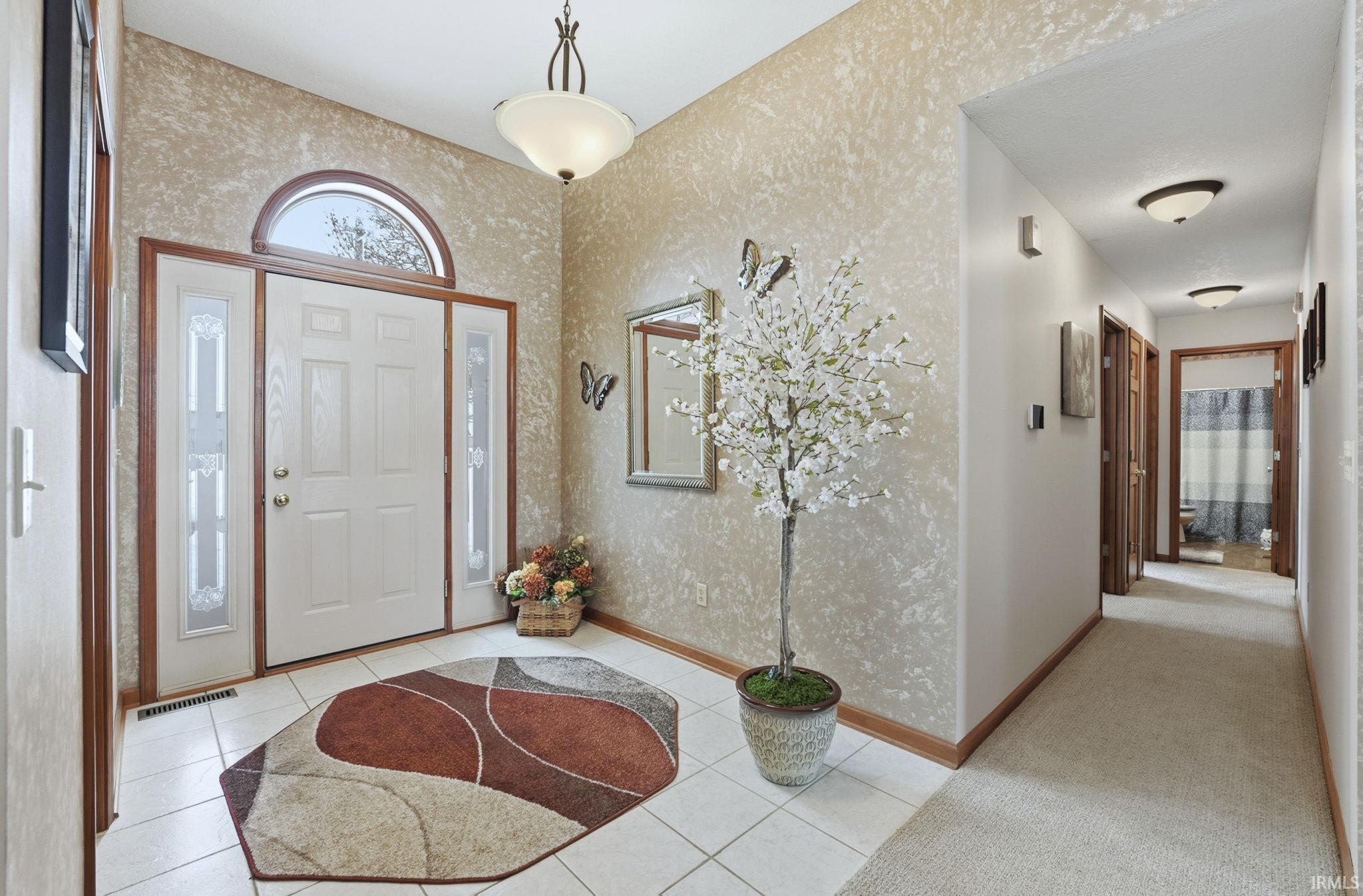 Foyer featuring plenty of natural light, wallpapered walls, and light tile patterned floors