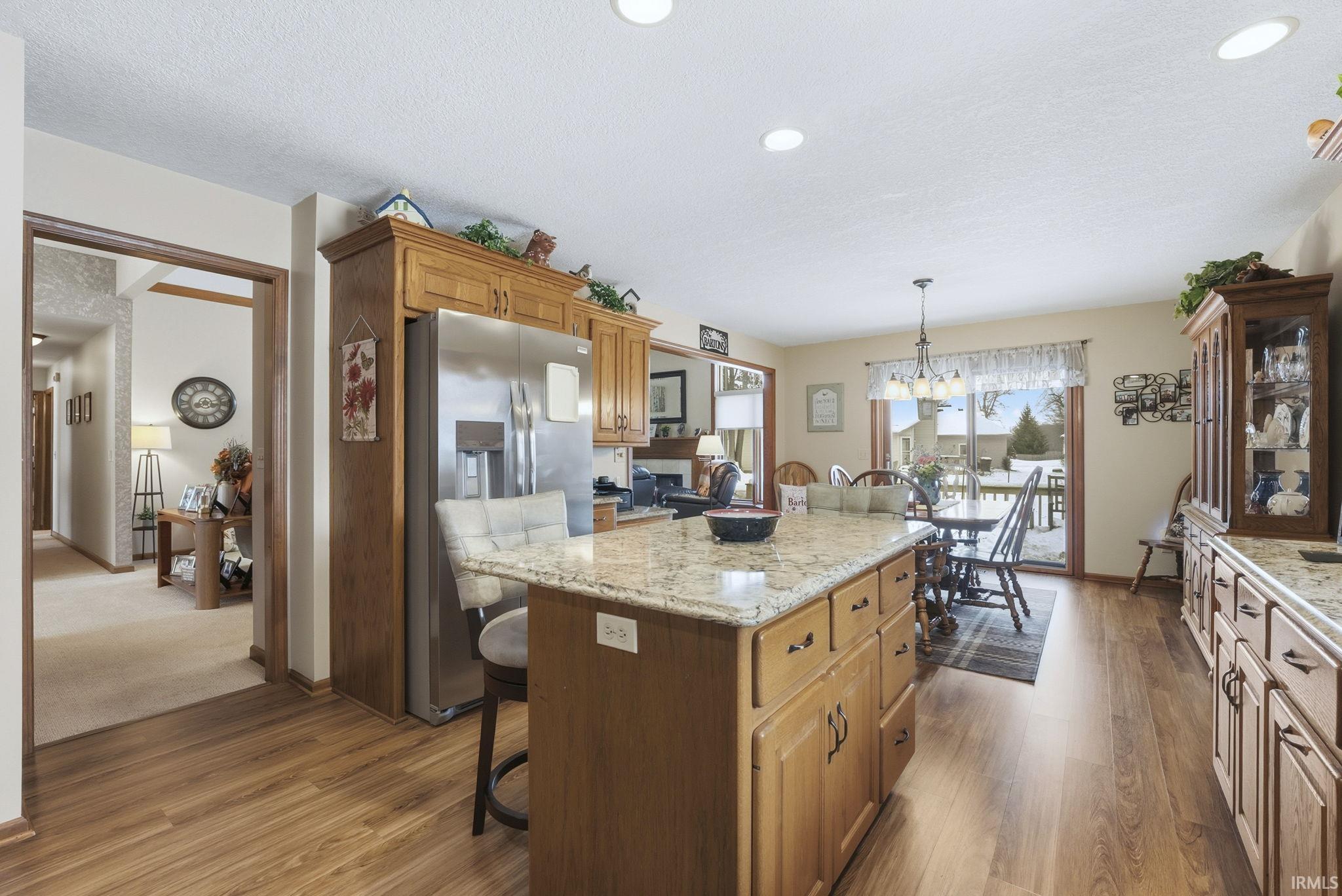 Kitchen featuring a breakfast bar area, a center island, stainless steel fridge, a textured ceiling, and light stone countertops