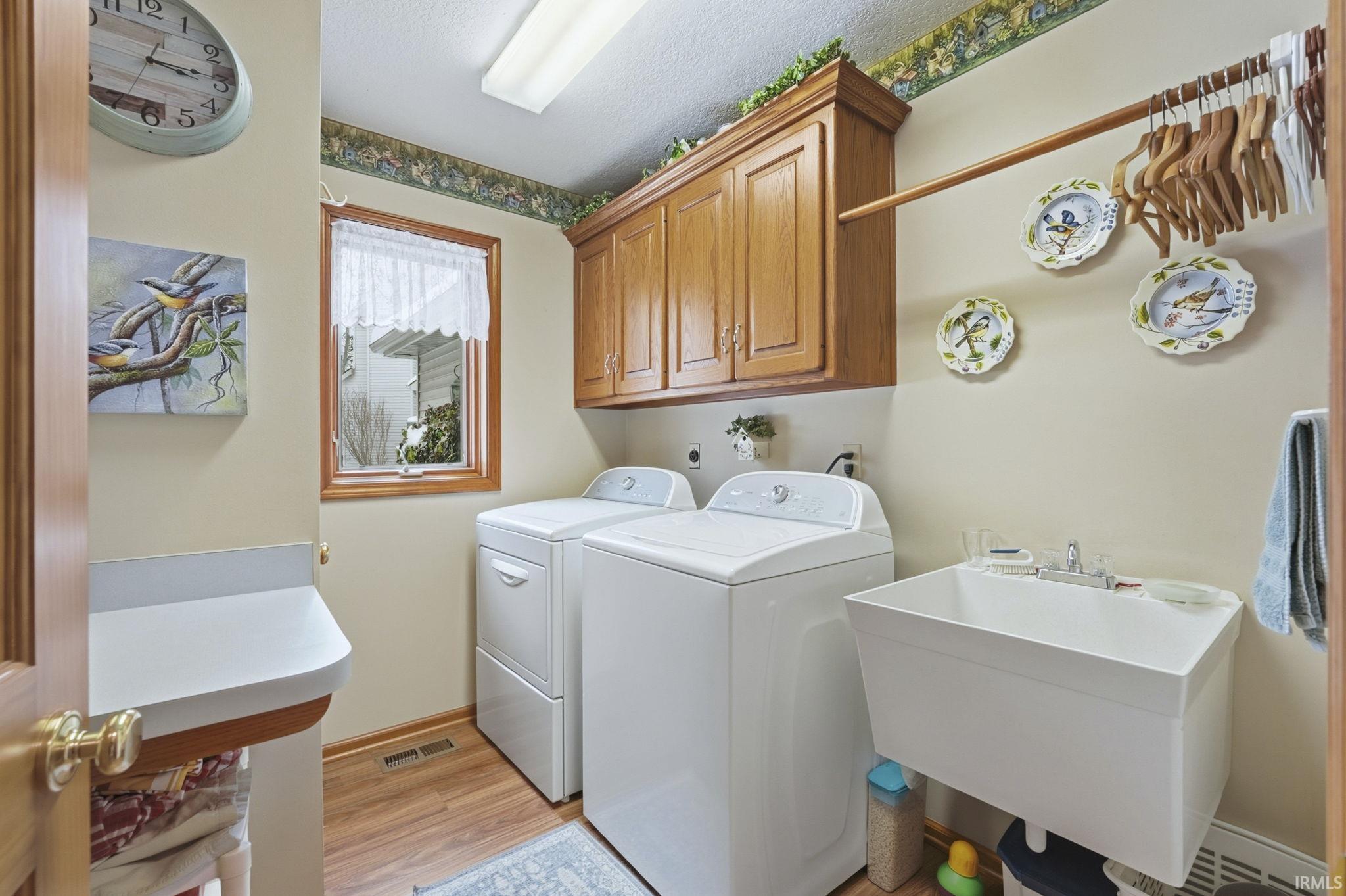Laundry area with cabinet space, light wood-type flooring, and washing machine and clothes dryer