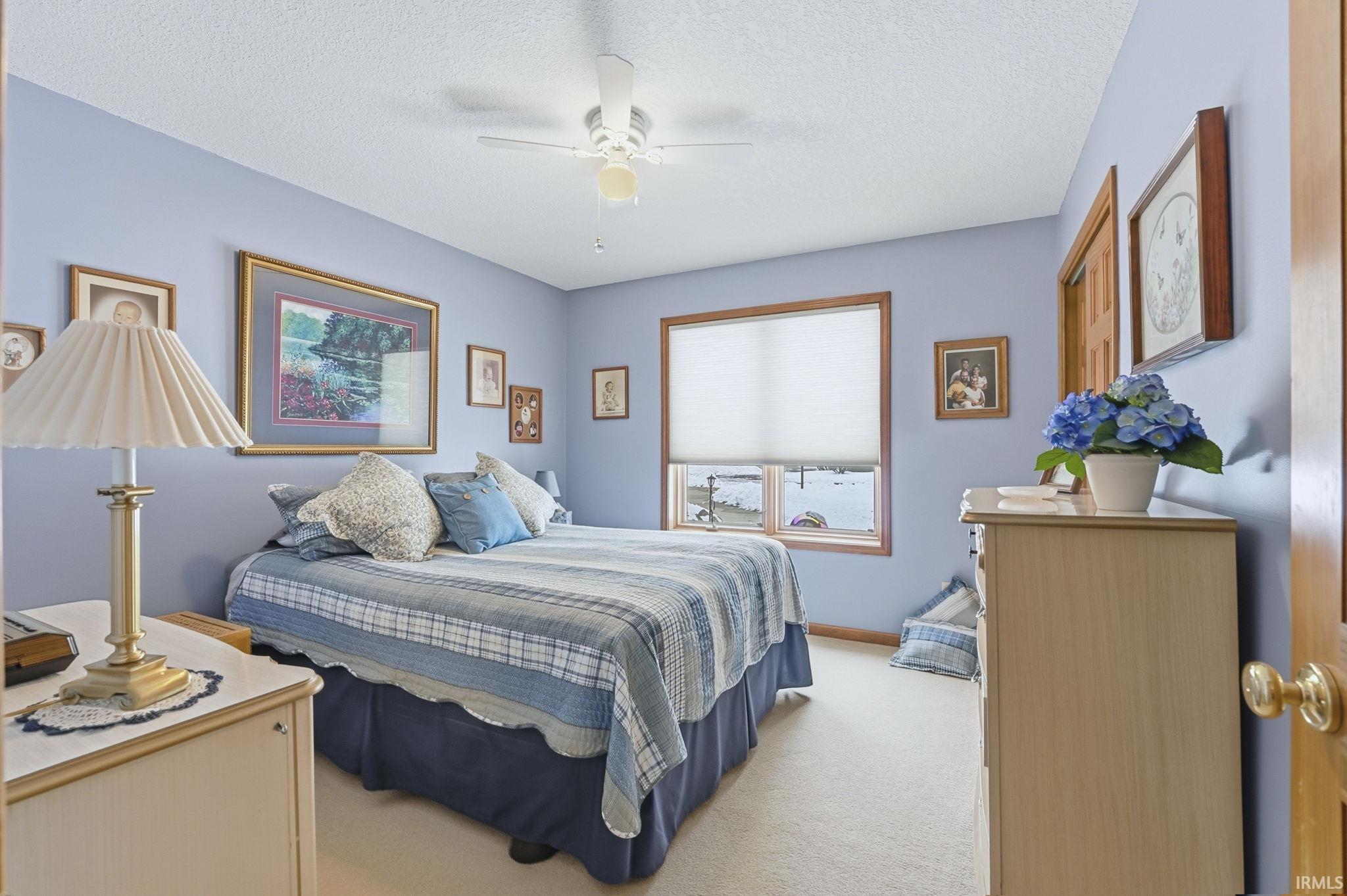 Bedroom featuring a textured ceiling, ceiling fan, and light carpet