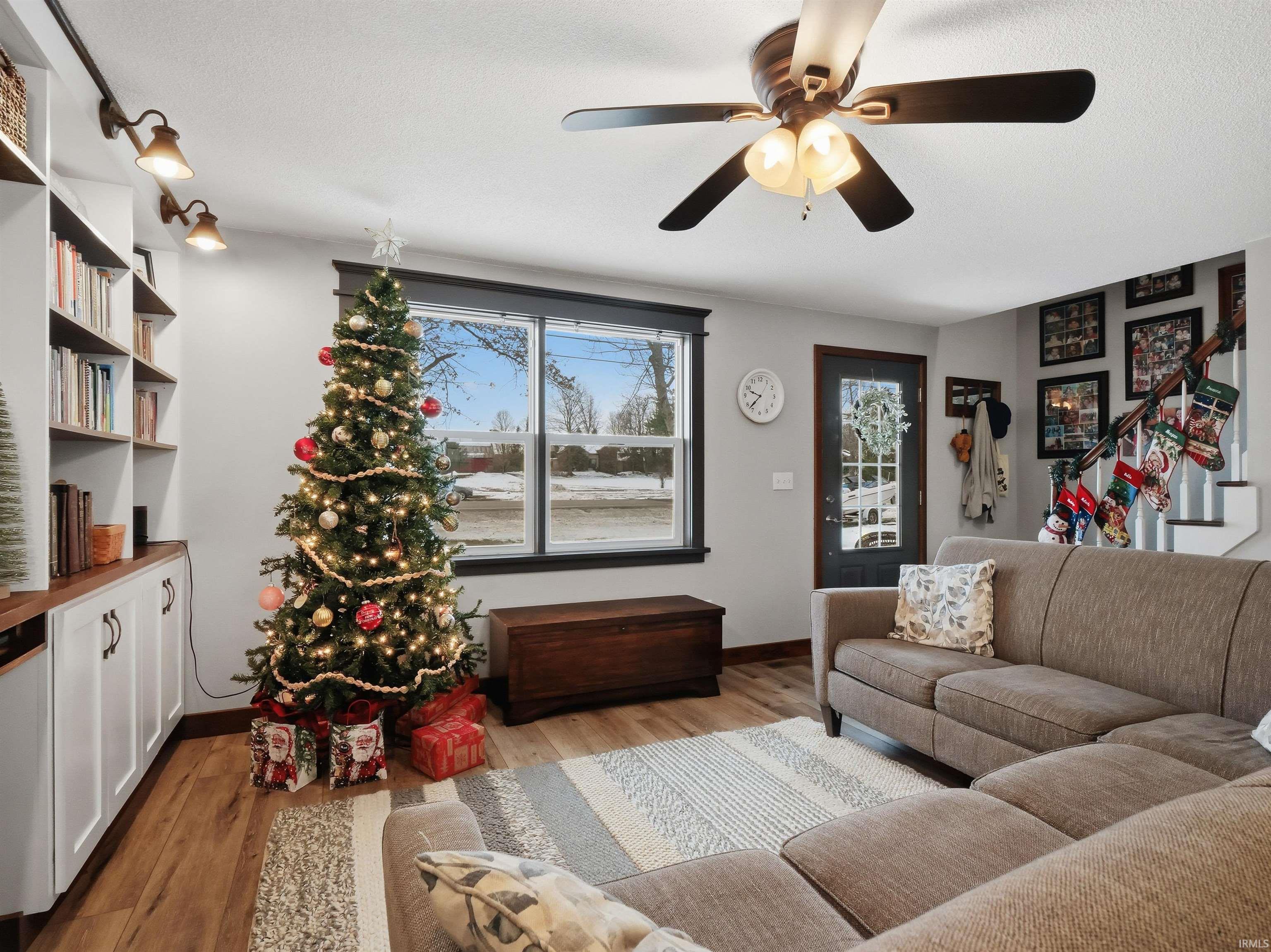 Living room featuring stairs, wood finished floors, a ceiling fan, and a textured ceiling