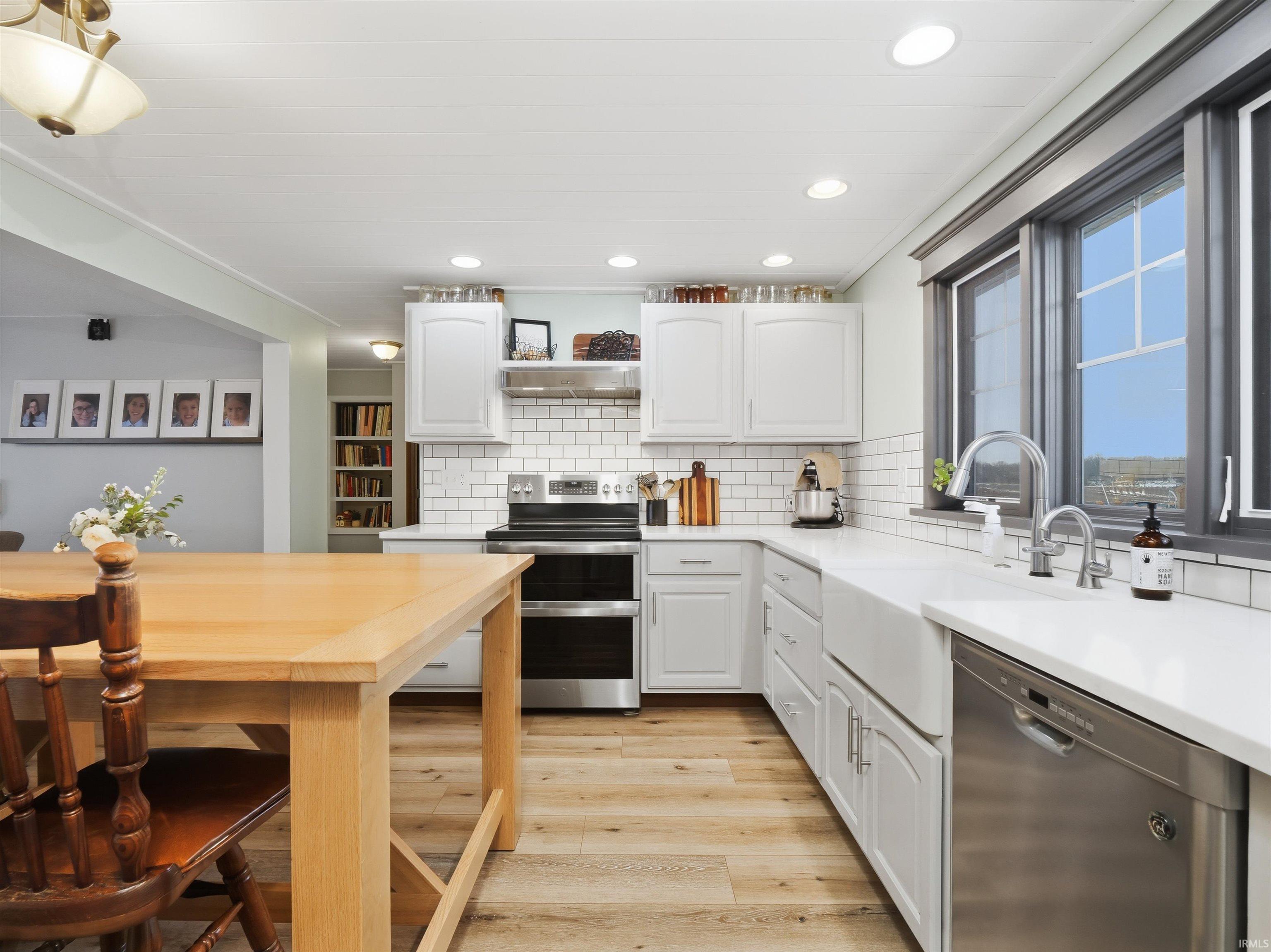 Kitchen with stainless steel appliances, updated cabinetry, recessed lighting, light wood finished floors, and decorative backsplash