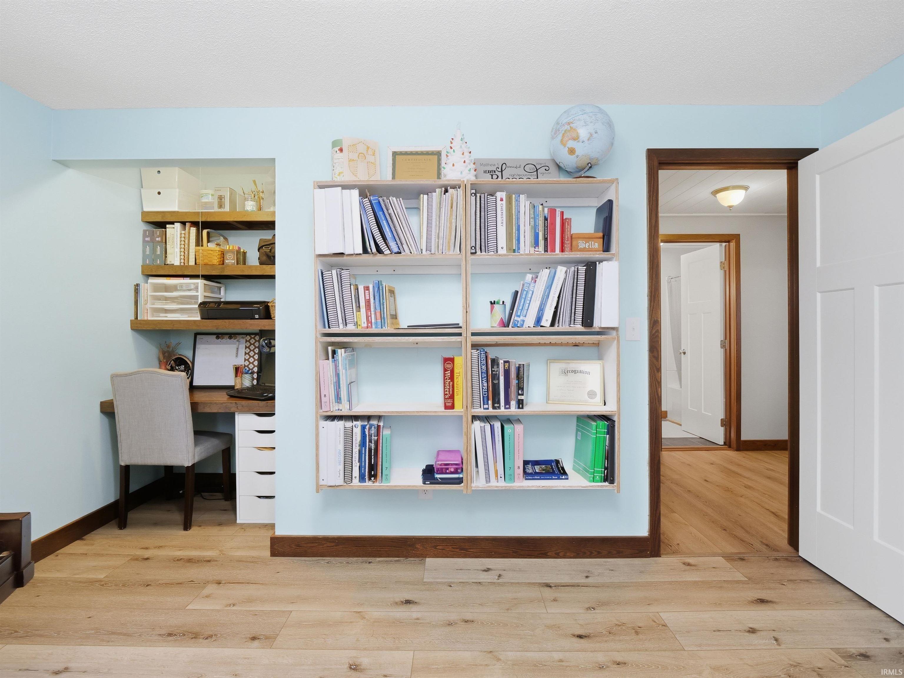 Home office with built in study area and light wood finished floors