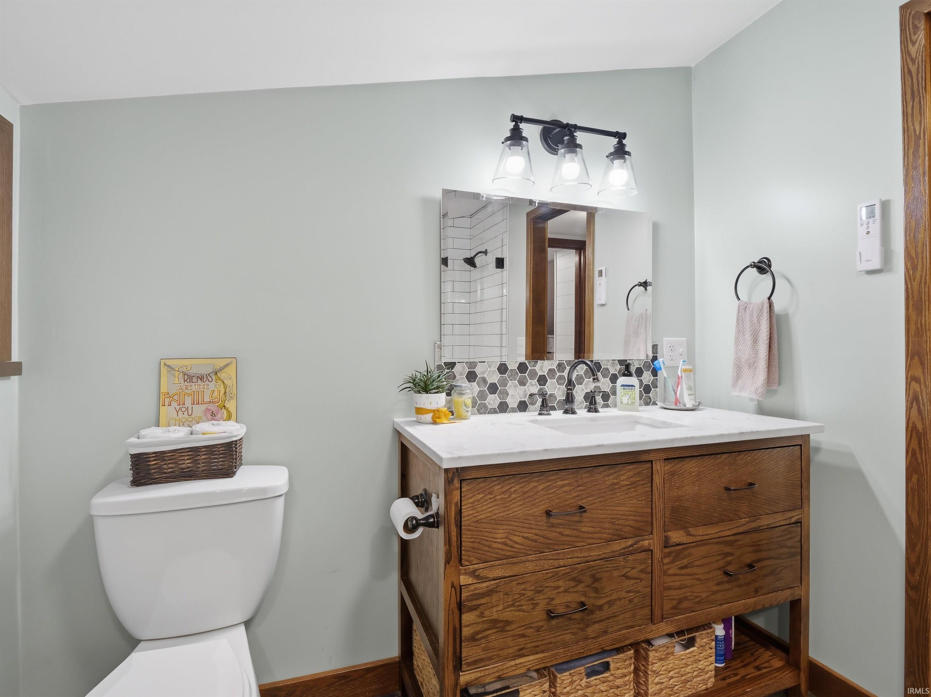 Full bathroom featuring vanity, backsplash, and tiled shower