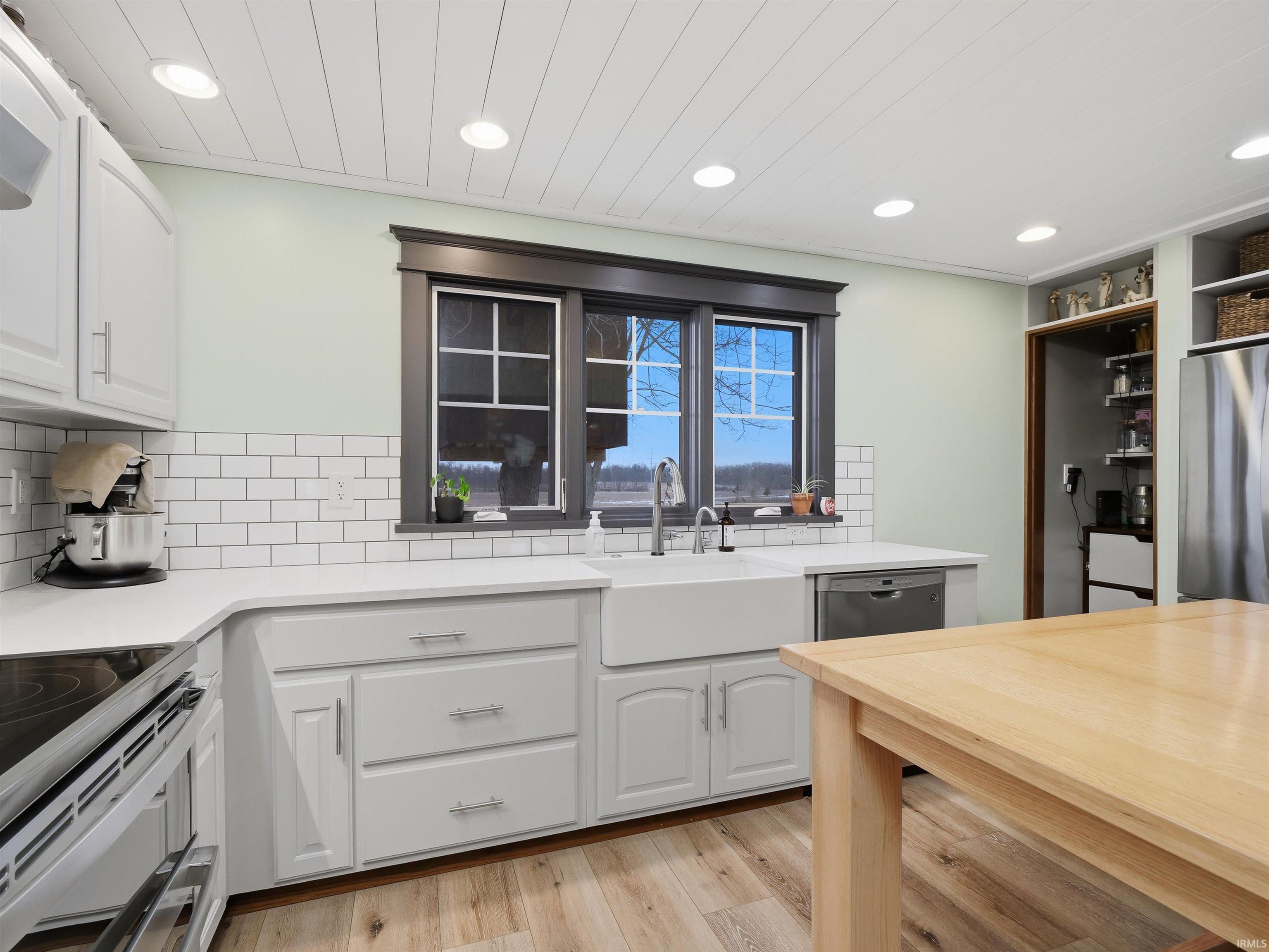 Kitchen with white cabinets, tasteful backsplash, appliances with stainless steel finishes, light wood-style floors, and recessed lighting