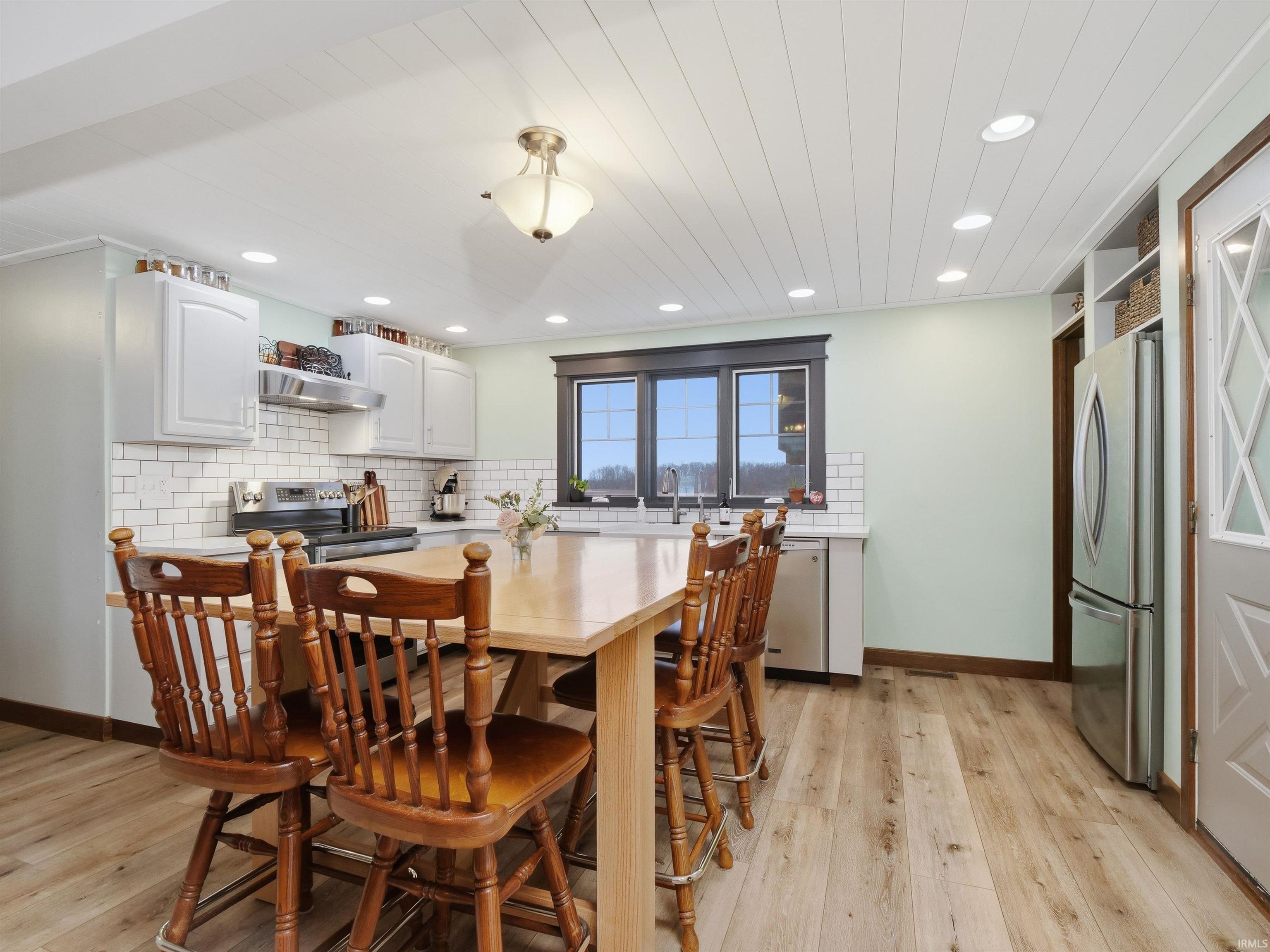 Dining area with light wood finished floors, ship-lap ceiling, and recessed lighting
