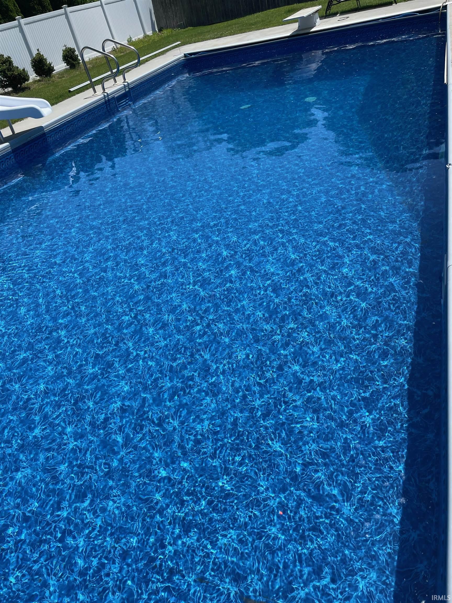 View of swimming pool with a diving board