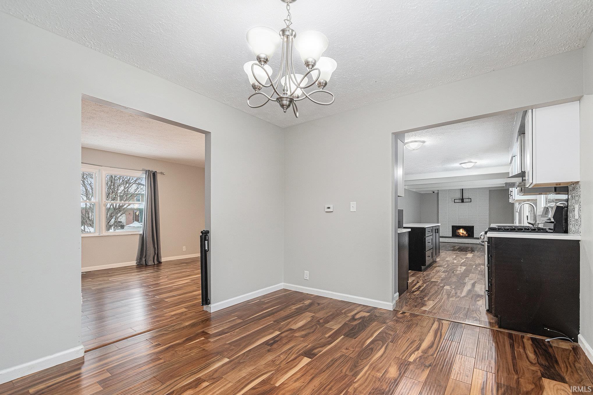 Unfurnished room with dark wood finished floors, a chandelier, and a textured ceiling