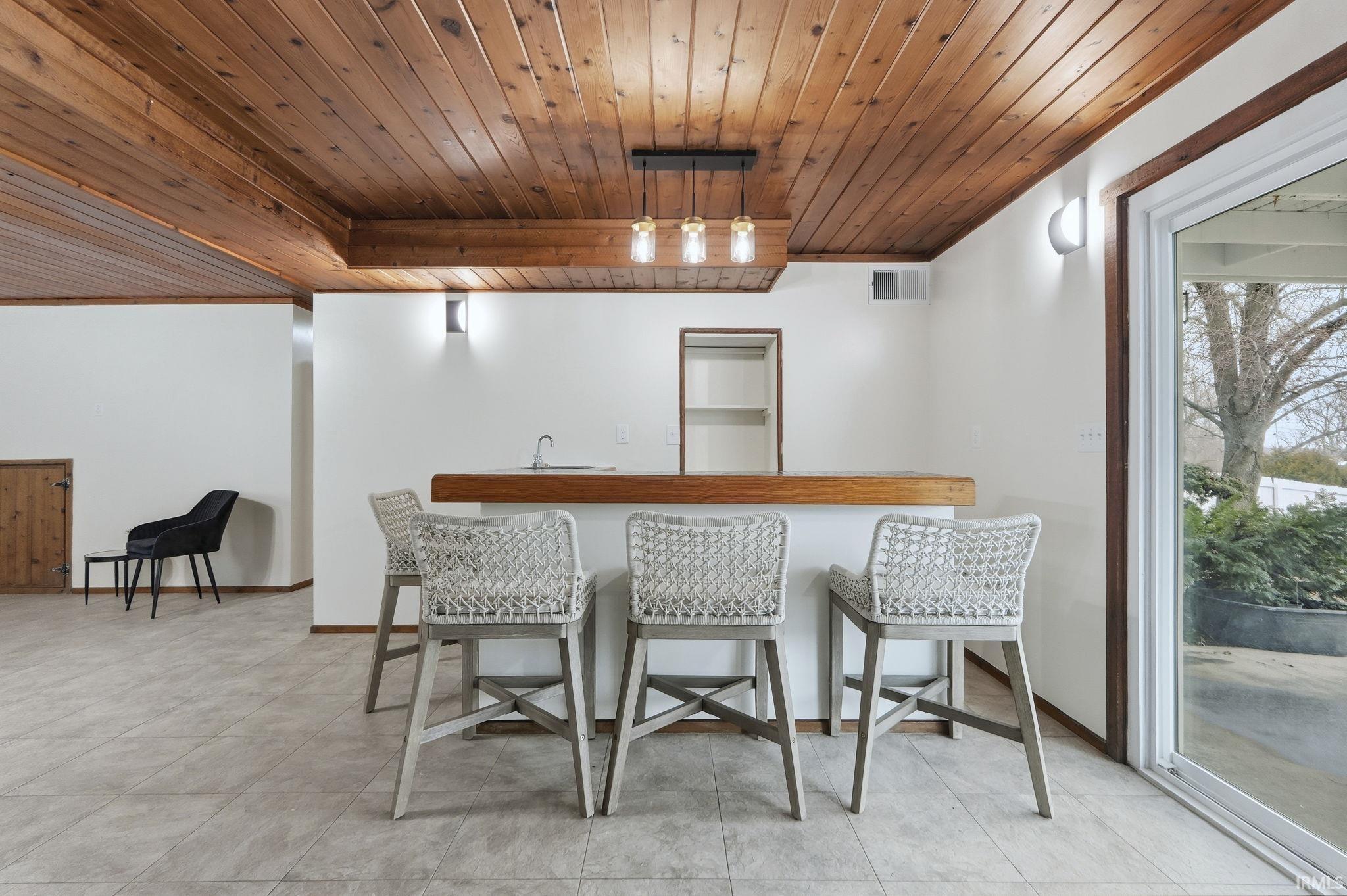 Indoor wet bar featuring wood ceiling, pendant lighting, butcher block countertops, light tile patterned floors, and open shelves
