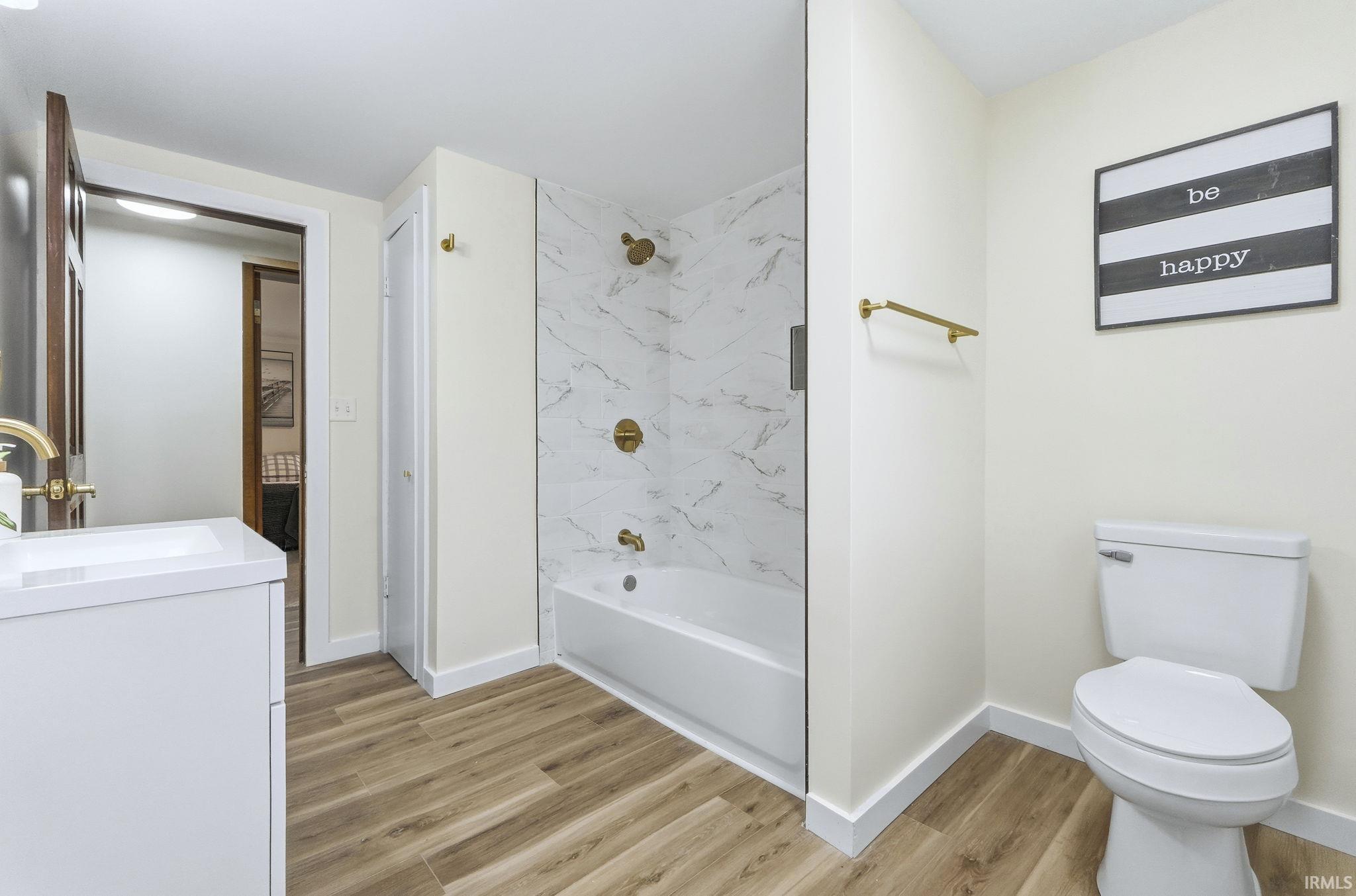 Bathroom with vanity, shower / tub combination, light wood-style flooring, and a closet