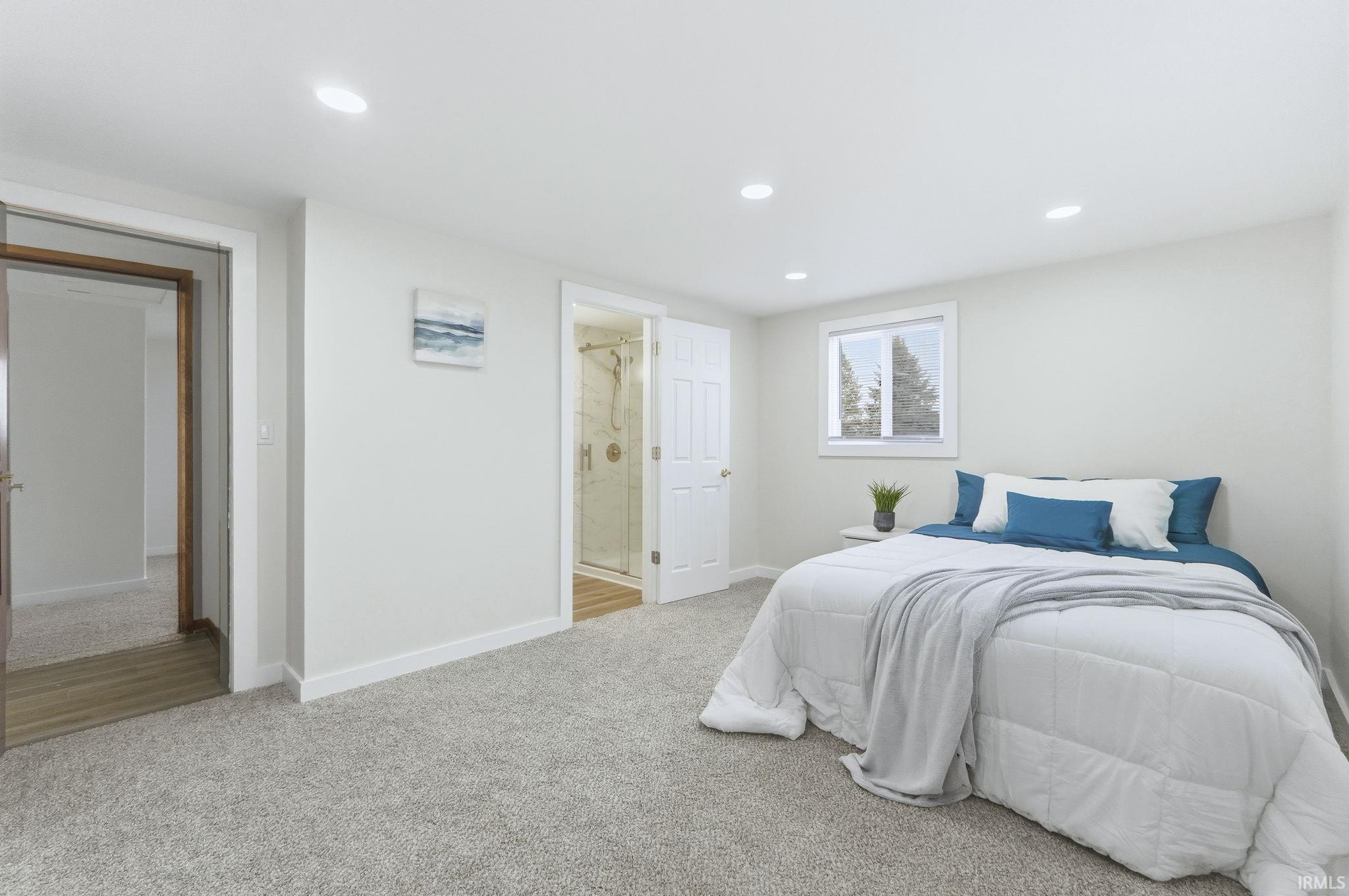 Bedroom featuring light colored carpet, ensuite bathroom, and recessed lighting