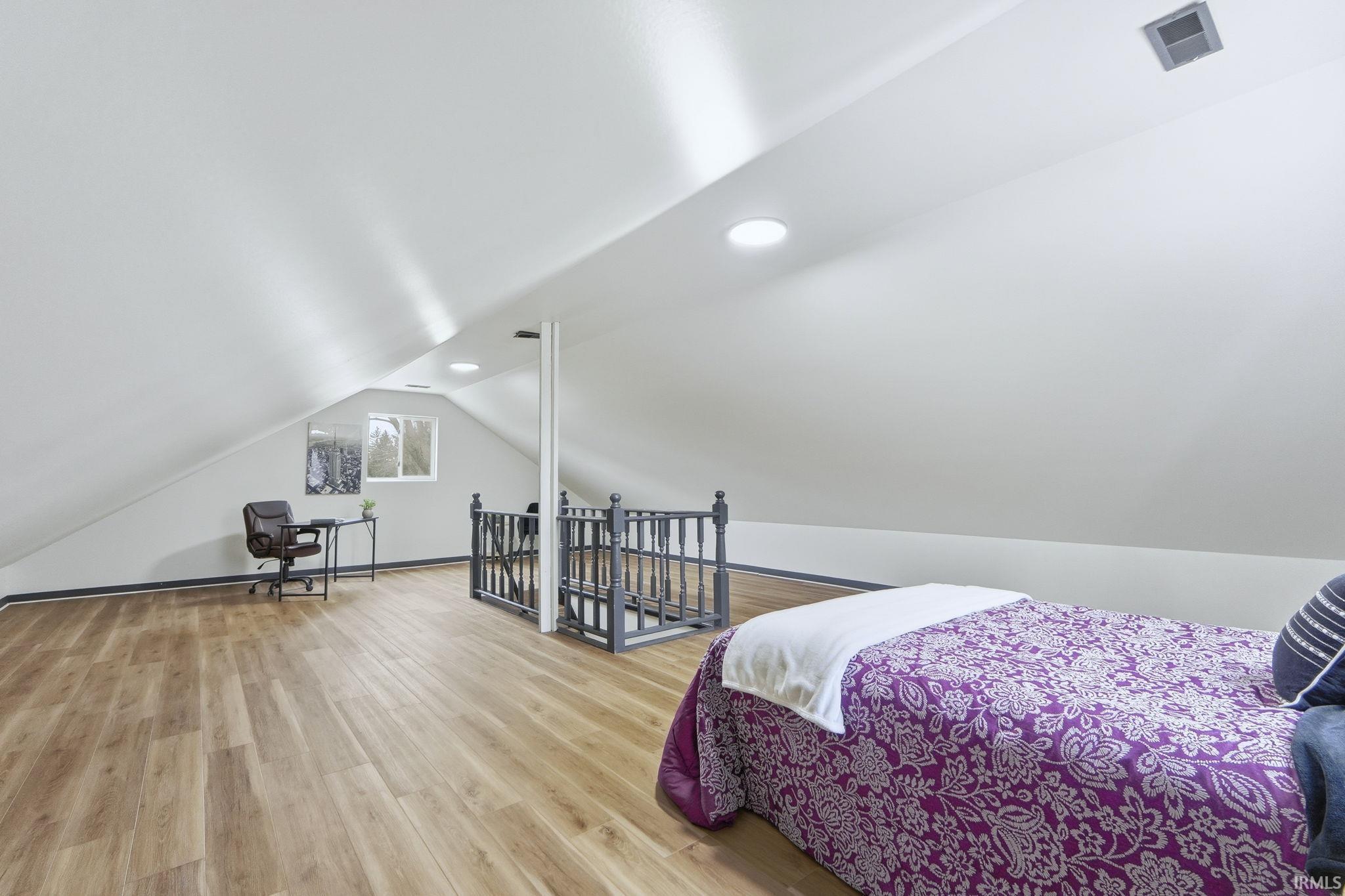 Bedroom featuring vaulted ceiling, wood finished floors, and recessed lighting