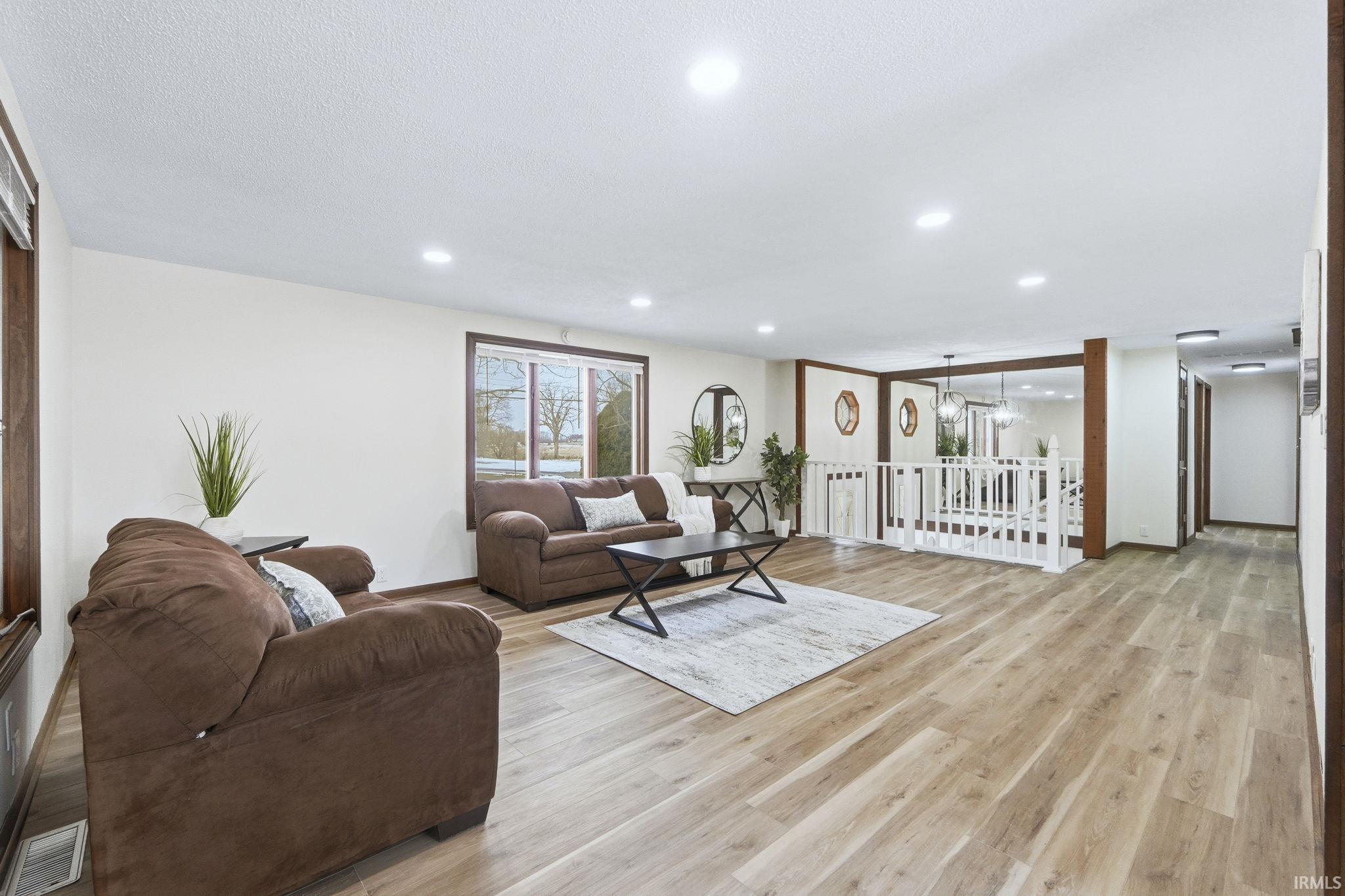 Living area with light wood finished floors, recessed lighting, and a textured ceiling