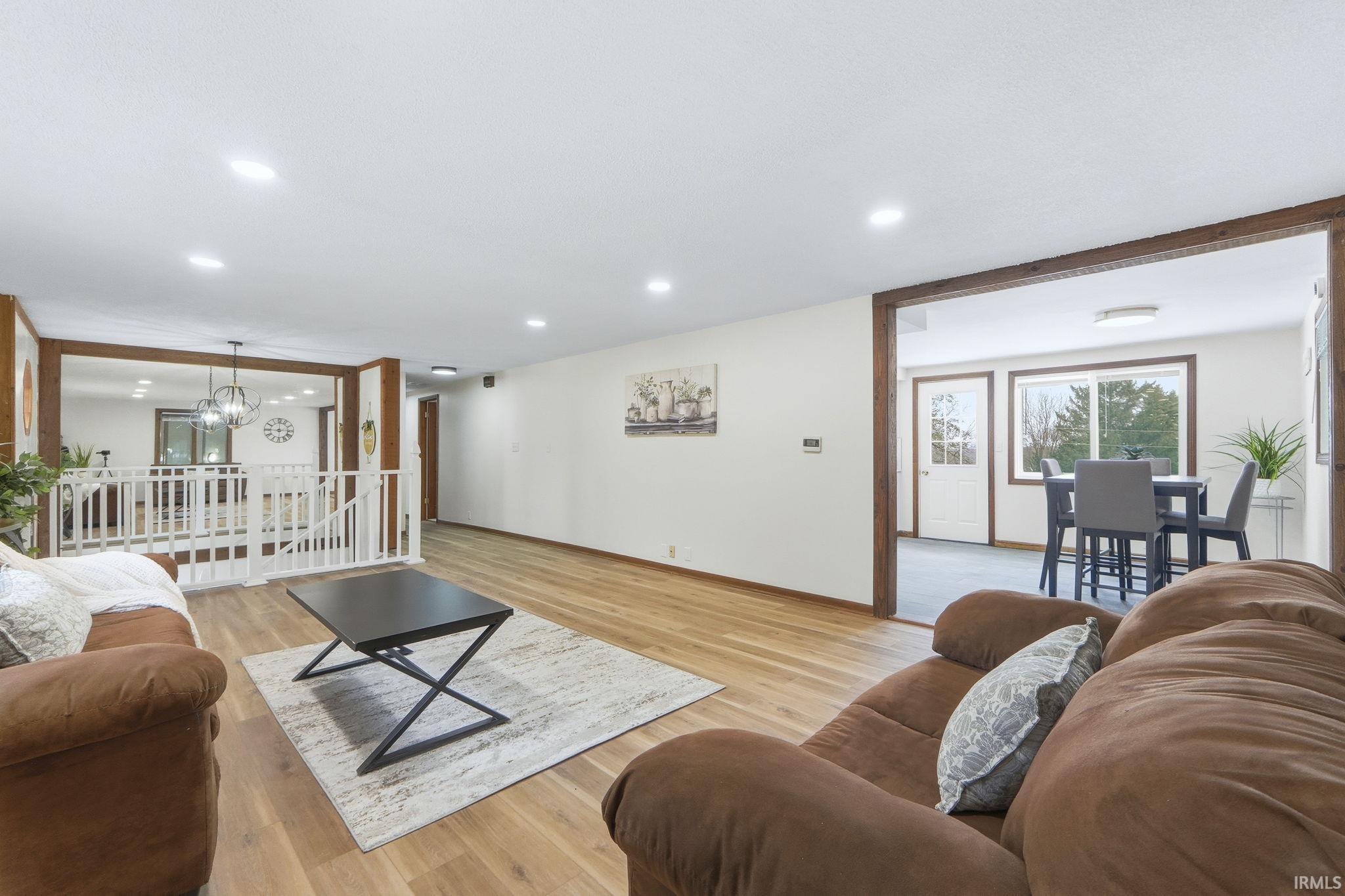 Living room featuring light wood finished floors, a chandelier, and recessed lighting
