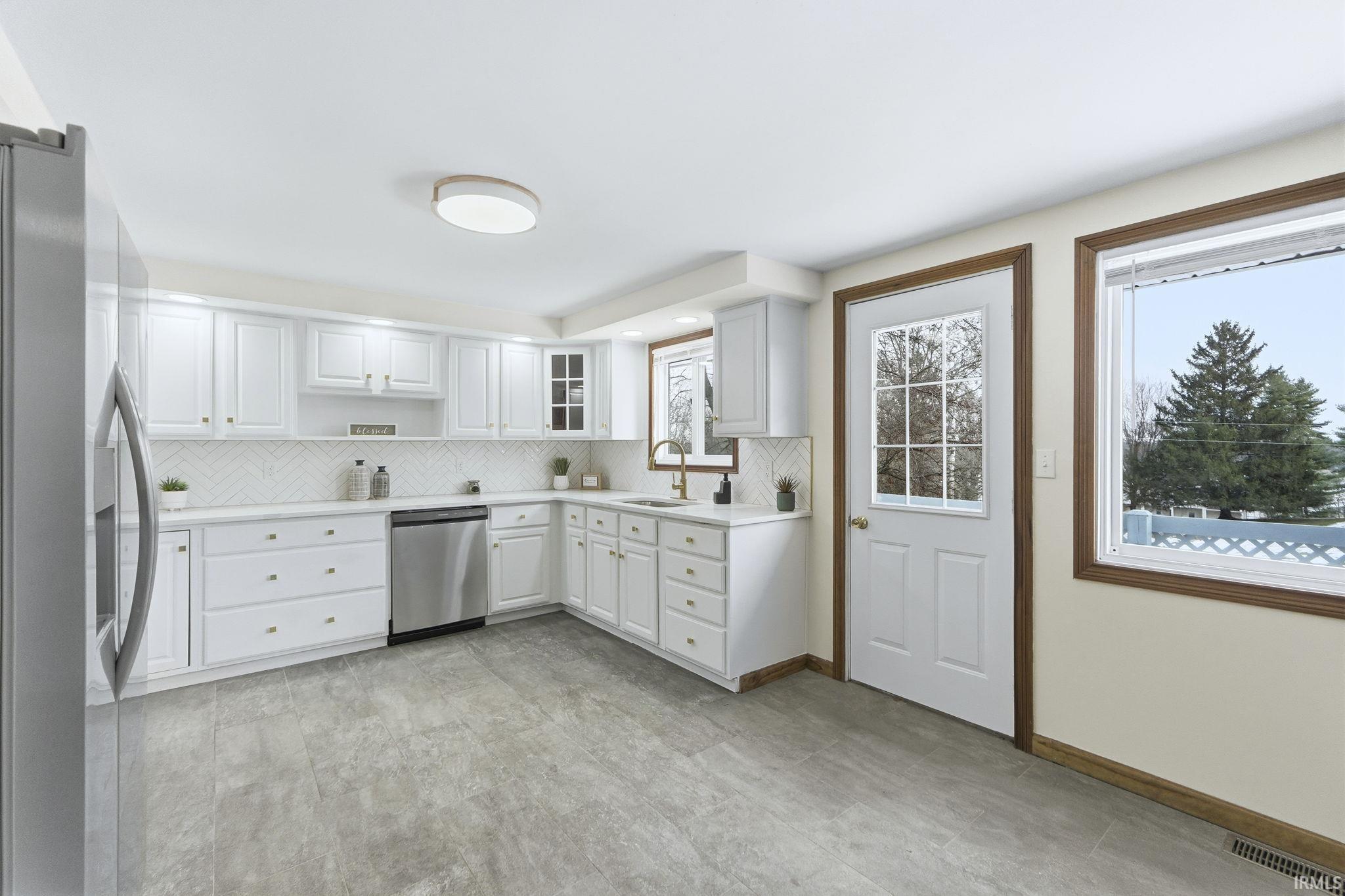 Kitchen featuring appliances with stainless steel finishes, light countertops, white cabinetry, and open shelves