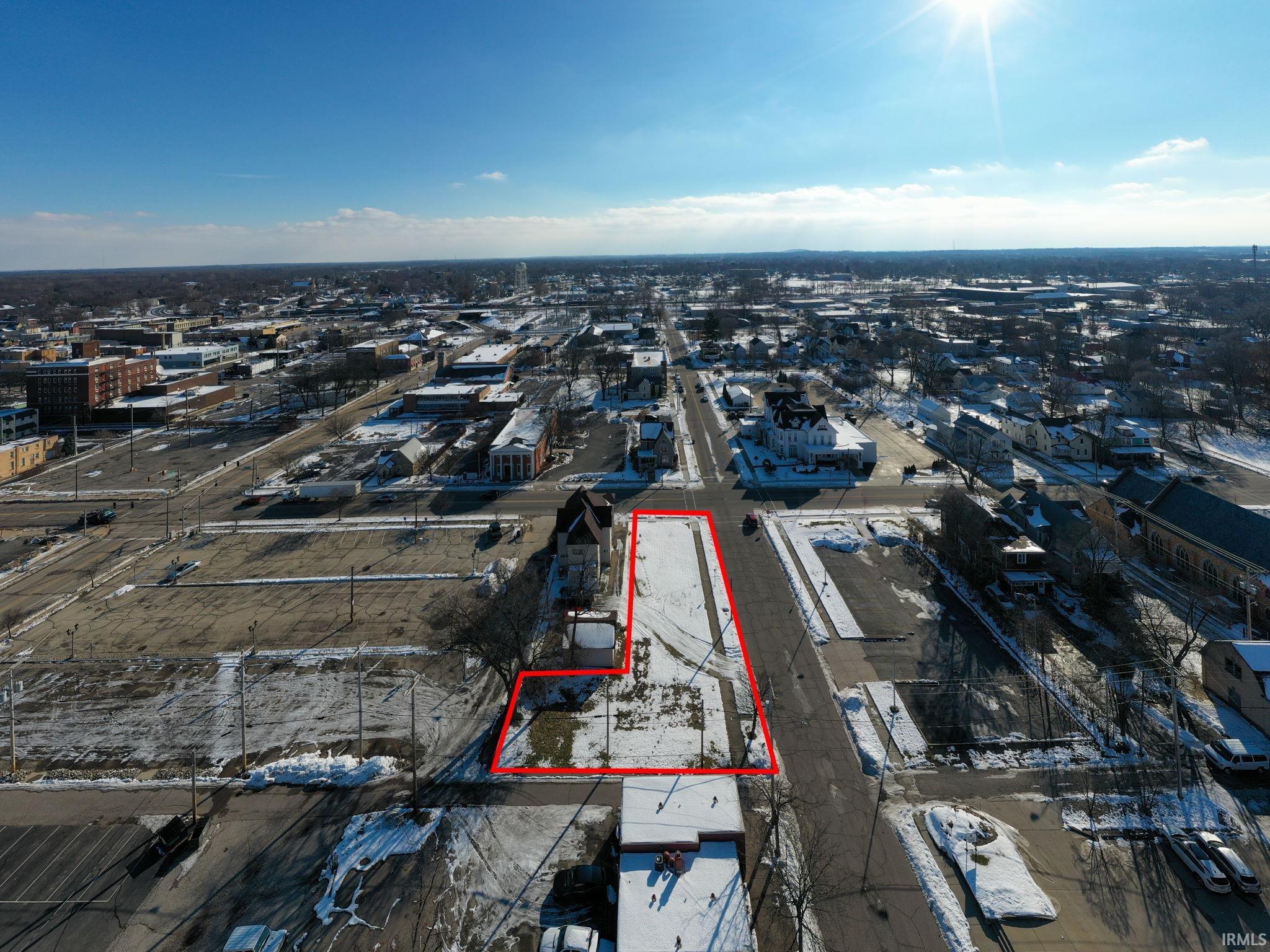 Aerial view of property and surrounding area featuring property parcel outlined and nearby urban area