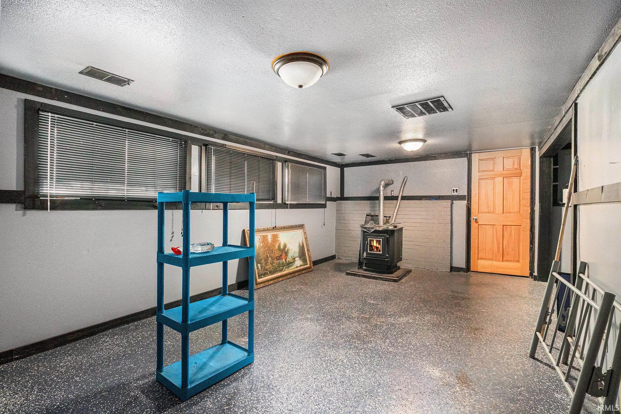 Basement featuring a wood stove and a textured ceiling