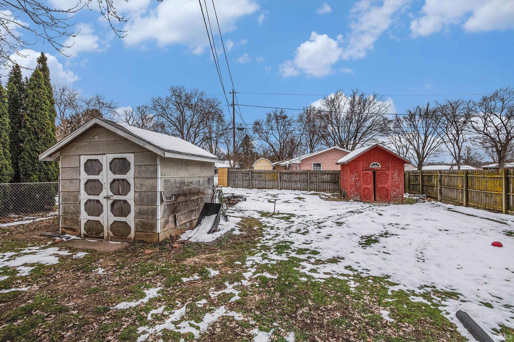 Yard layered in snow with a shed and a fenced backyard