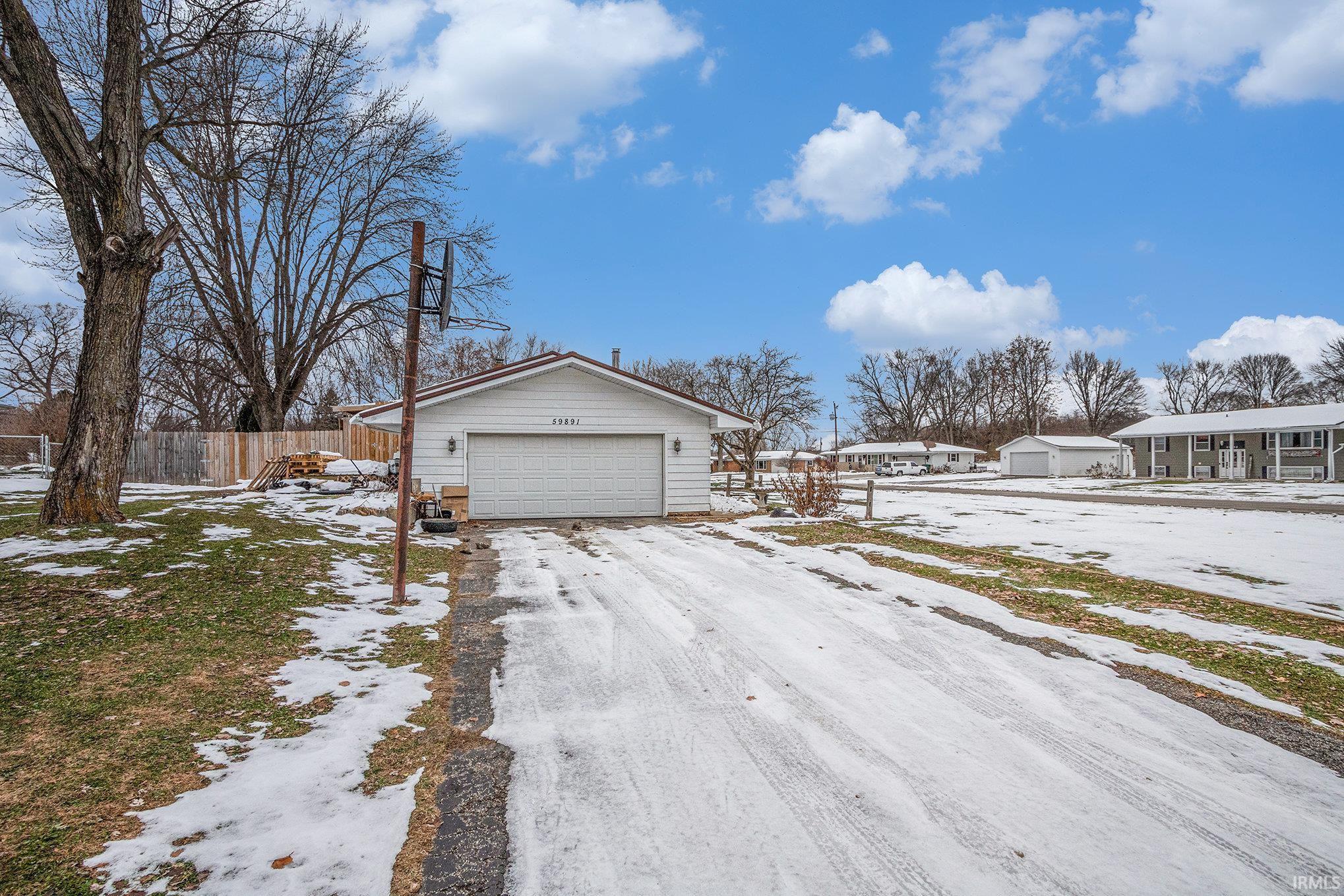 Snow covered property with a detached garage and an outbuilding