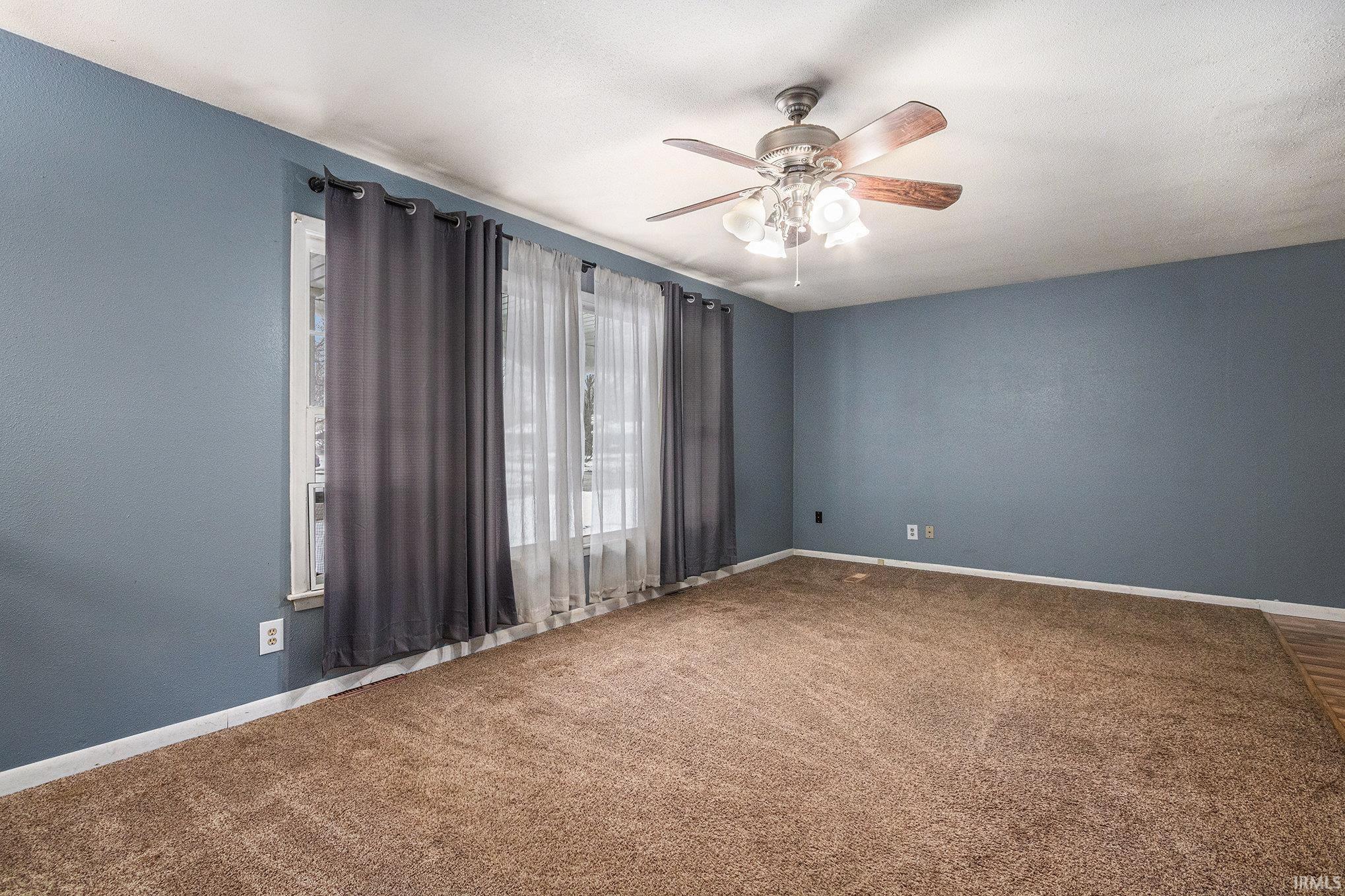 Carpeted spare room featuring baseboards and ceiling fan