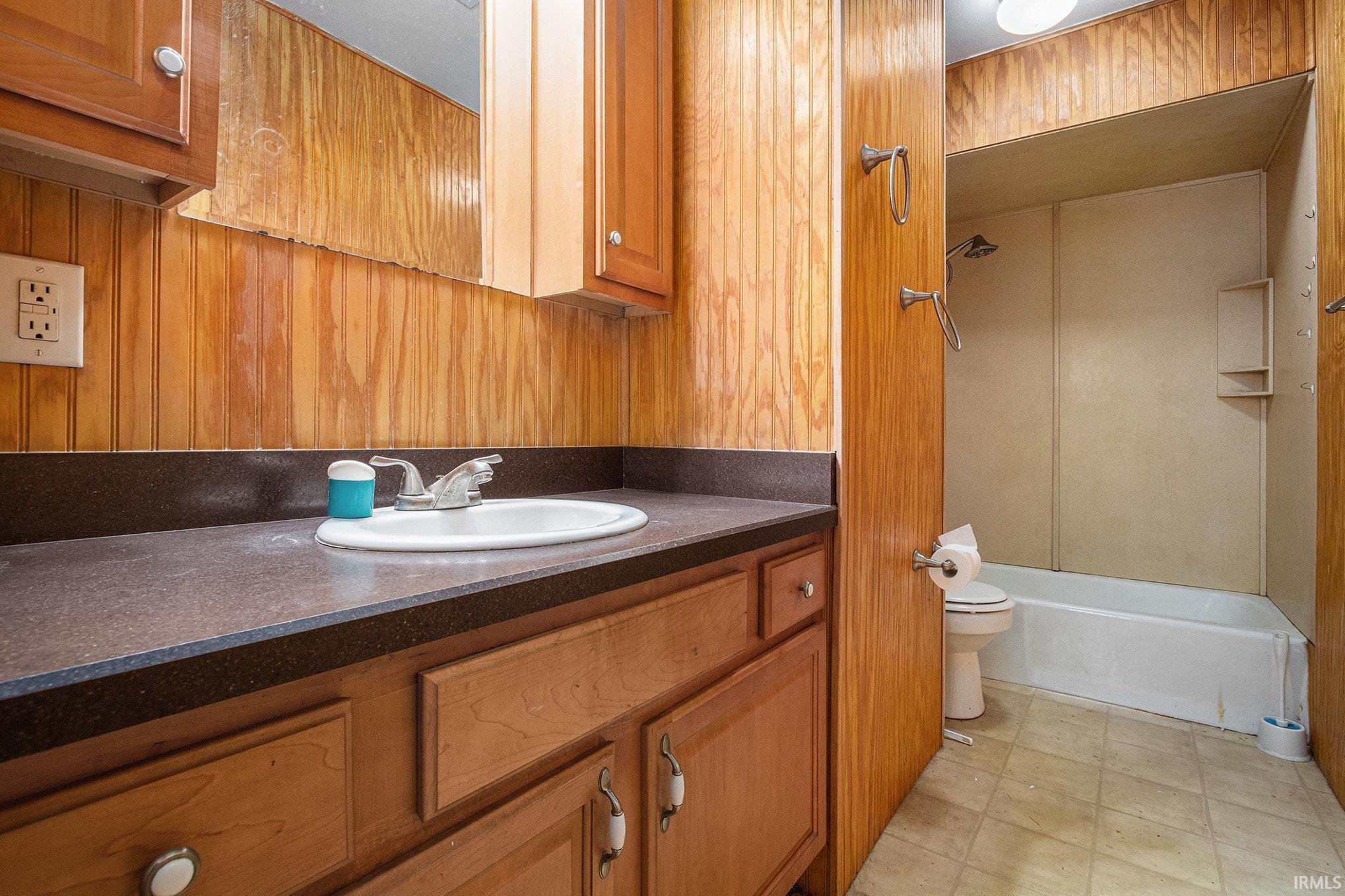 Full bathroom with vanity, bathing tub / shower combination, and wood walls