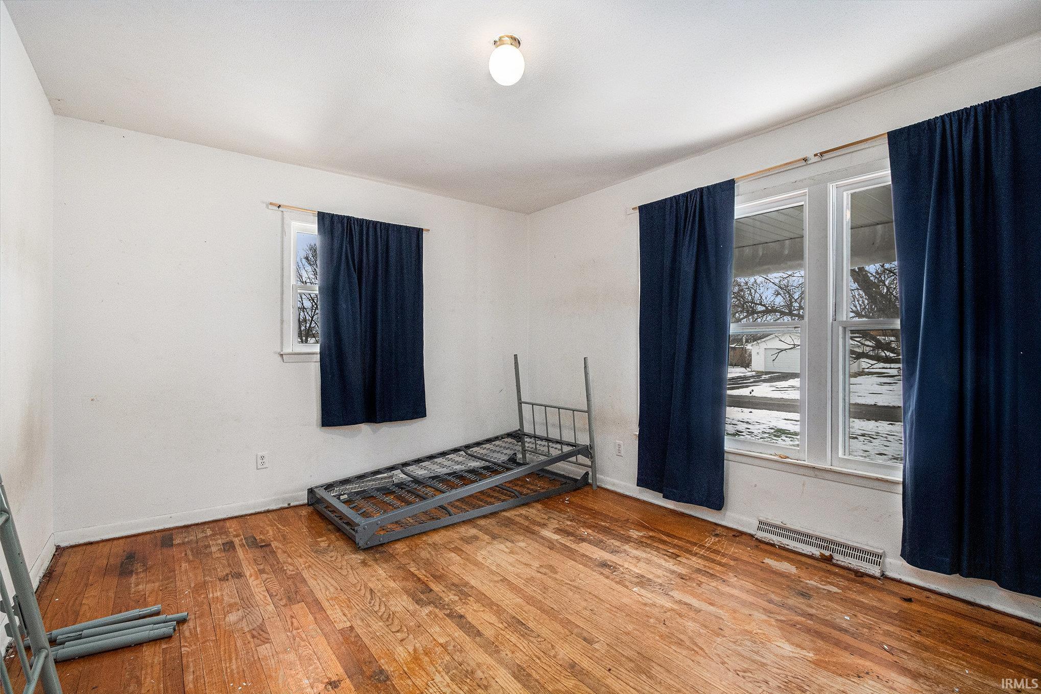 Unfurnished bedroom with hardwood / wood-style floors and multiple windows
