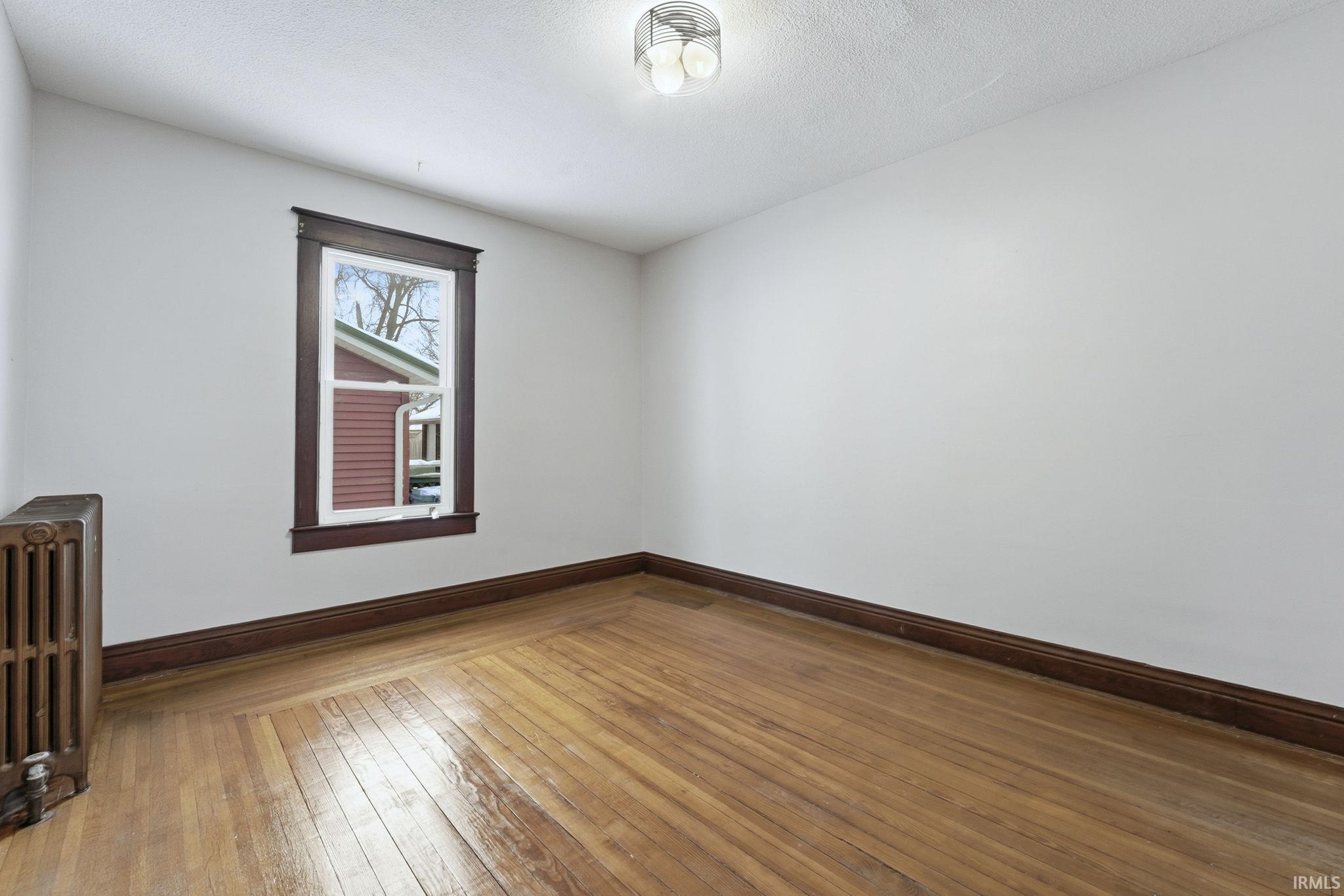 Unfurnished room with wood-type flooring, radiator, and a textured ceiling