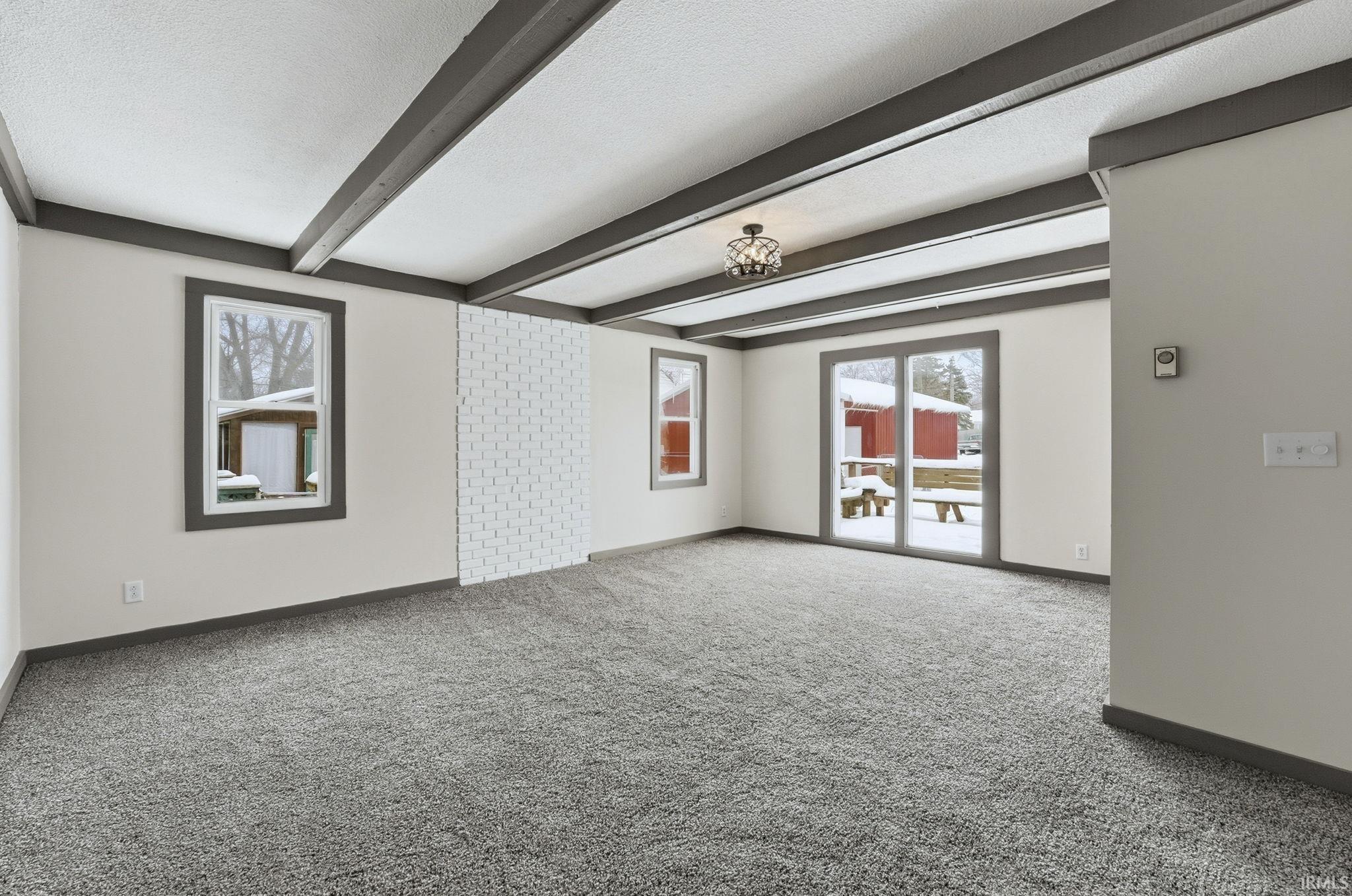 Spare room with carpet flooring, beamed ceiling, and a textured ceiling
