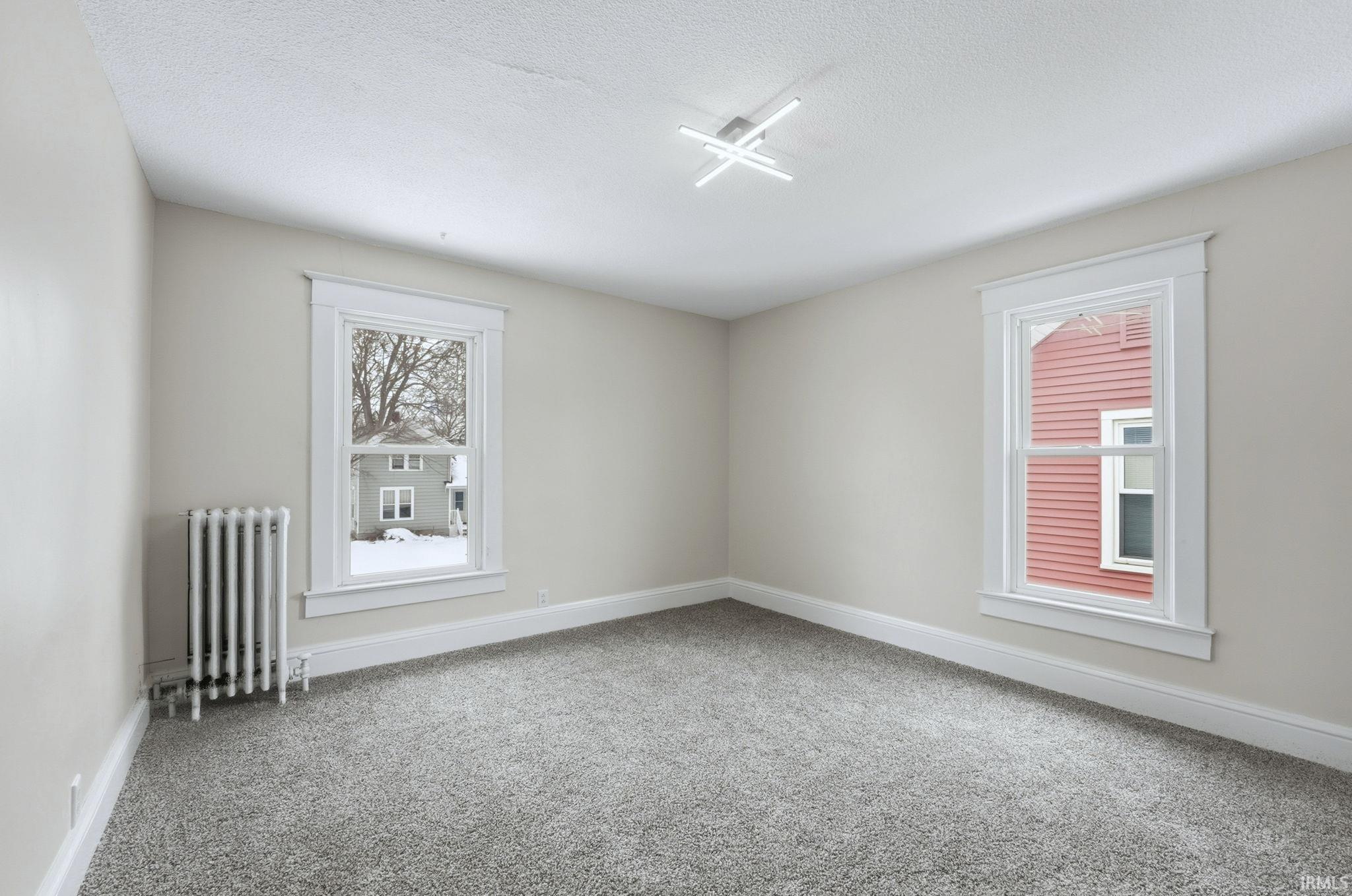 Unfurnished room with radiator heating unit, carpet, and a textured ceiling