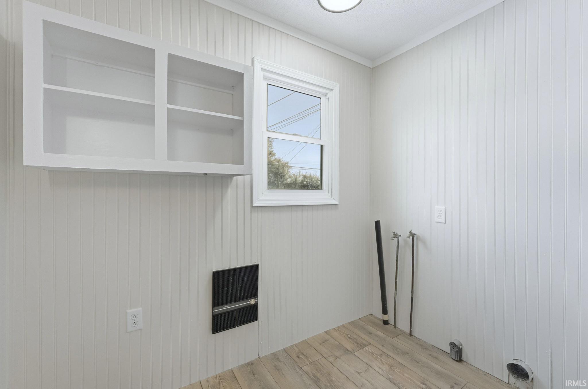 Washroom featuring light wood-style floors, wood walls, and ornamental molding