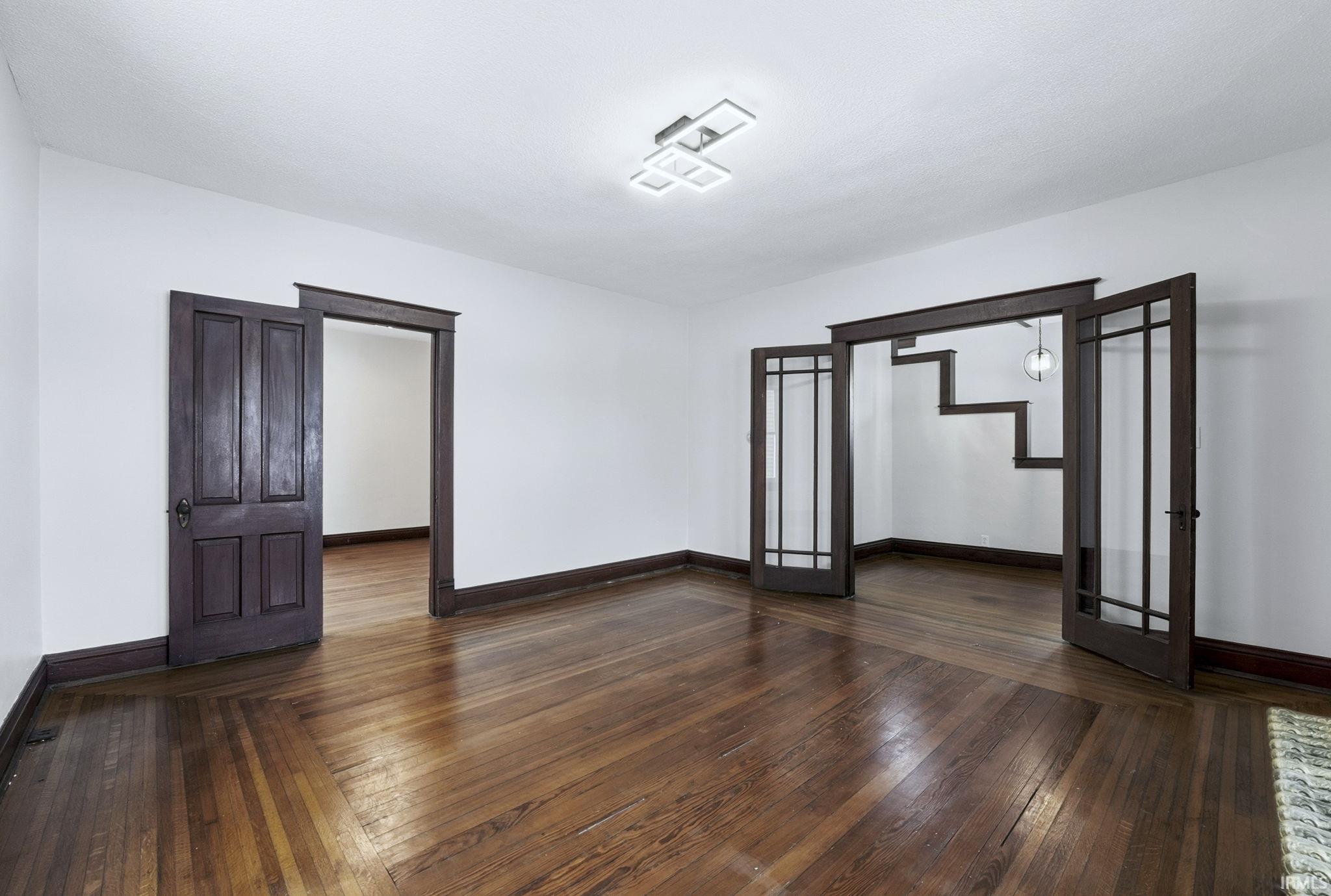 Empty room featuring french doors and dark wood-type flooring