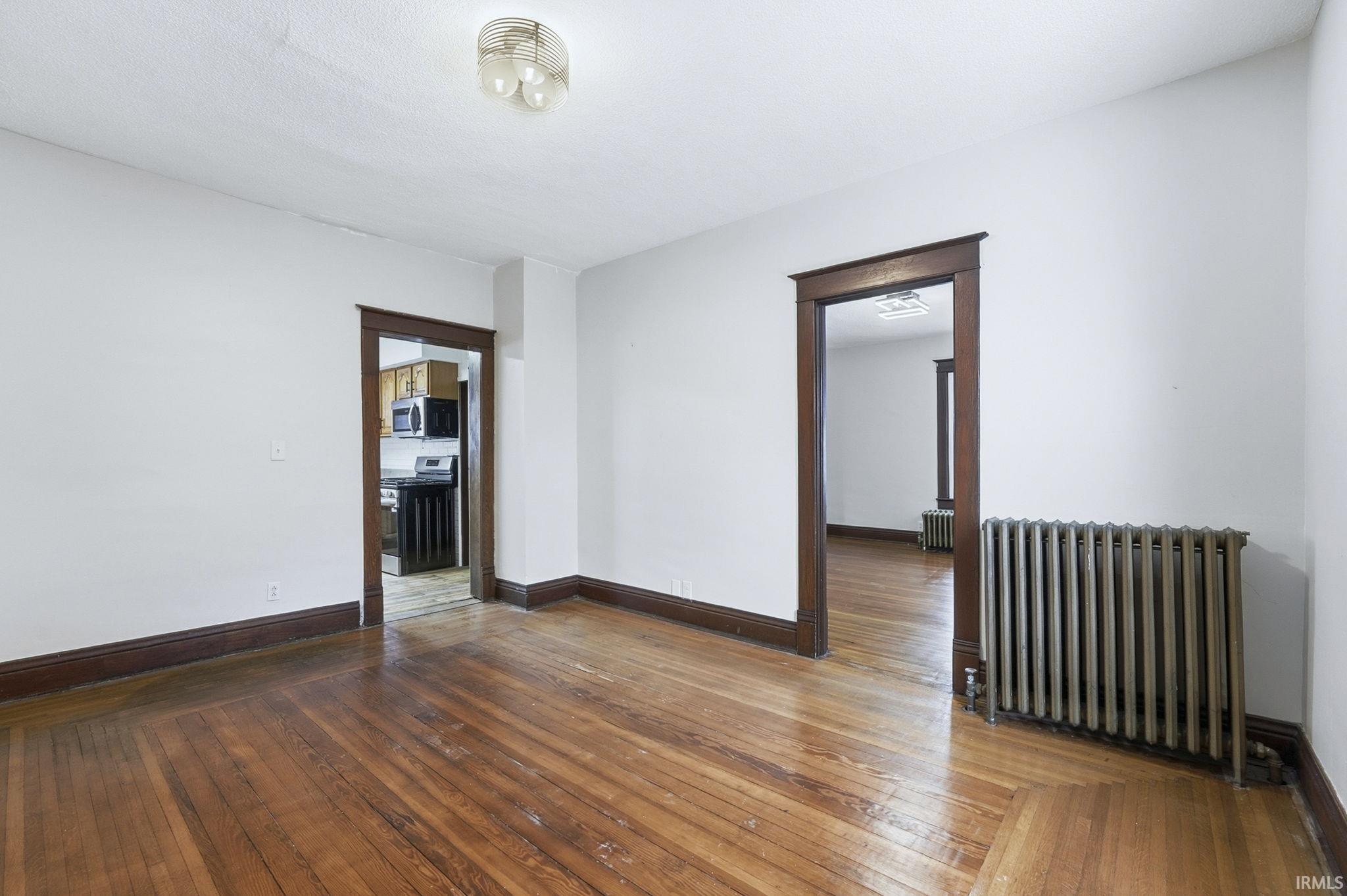 Empty room with radiator heating unit and dark wood finished floors