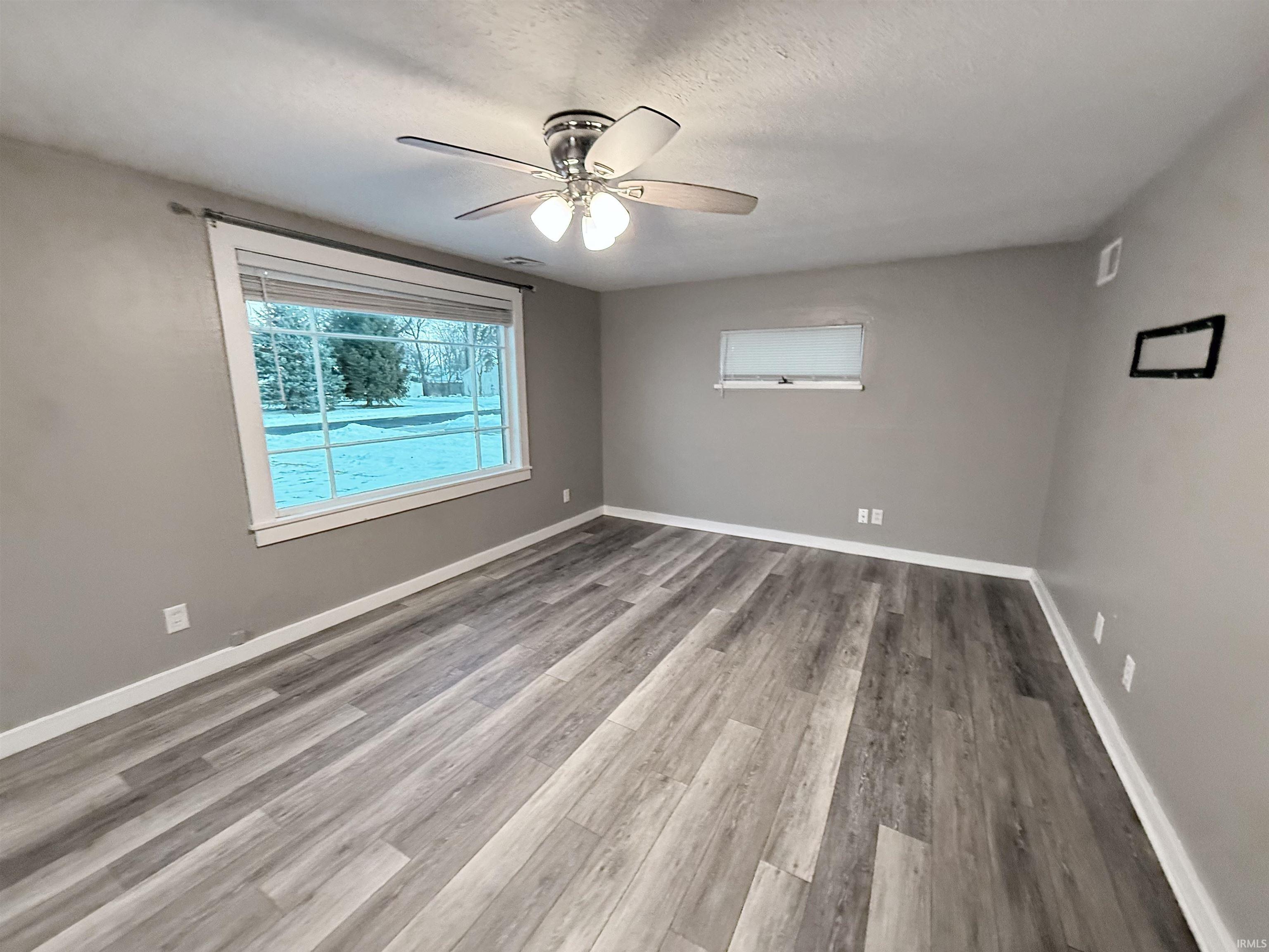 Empty room featuring light wood-style flooring, a textured ceiling, and ceiling fan