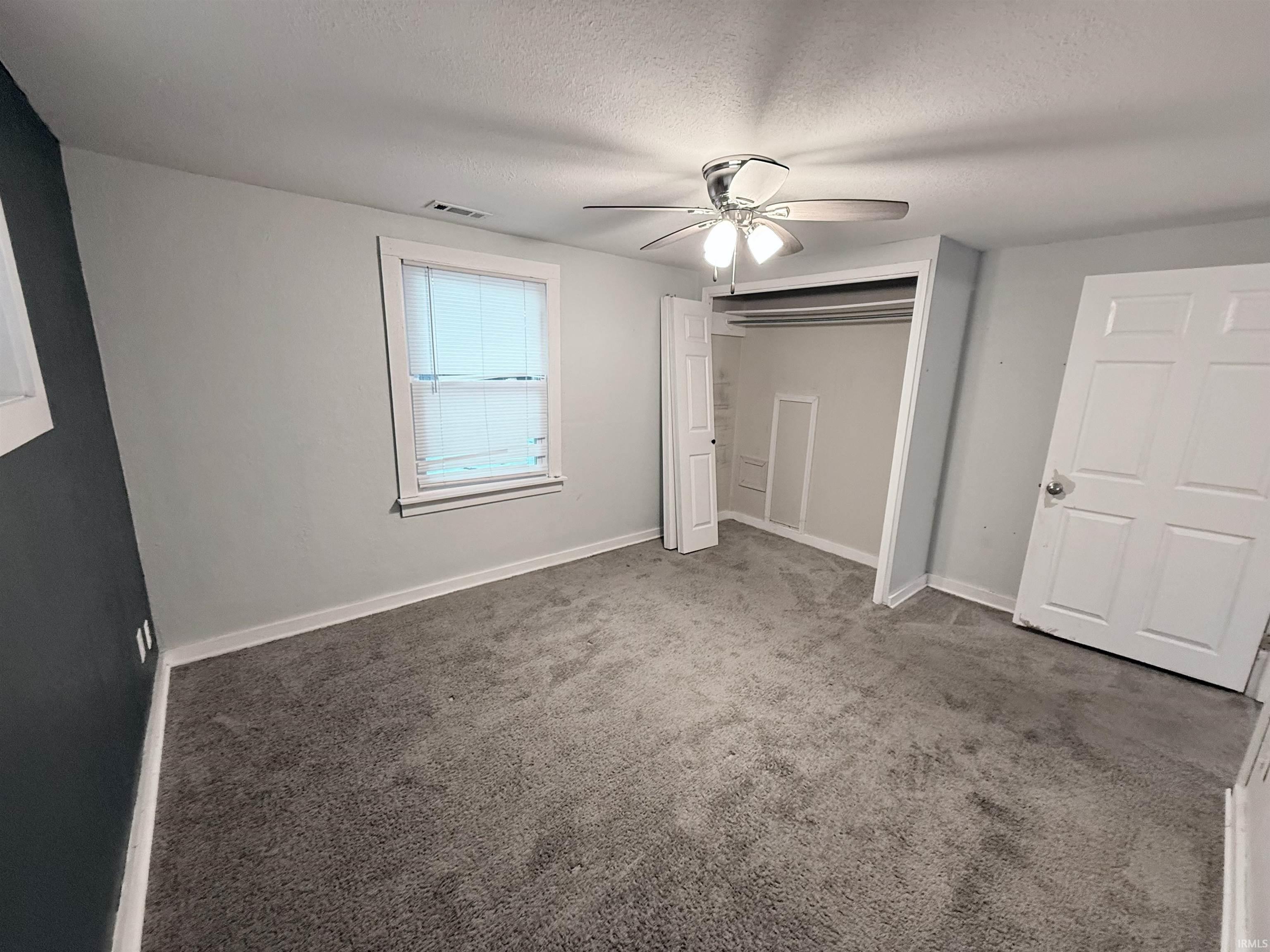 Unfurnished bedroom featuring a textured ceiling, a ceiling fan, carpet flooring, and a closet