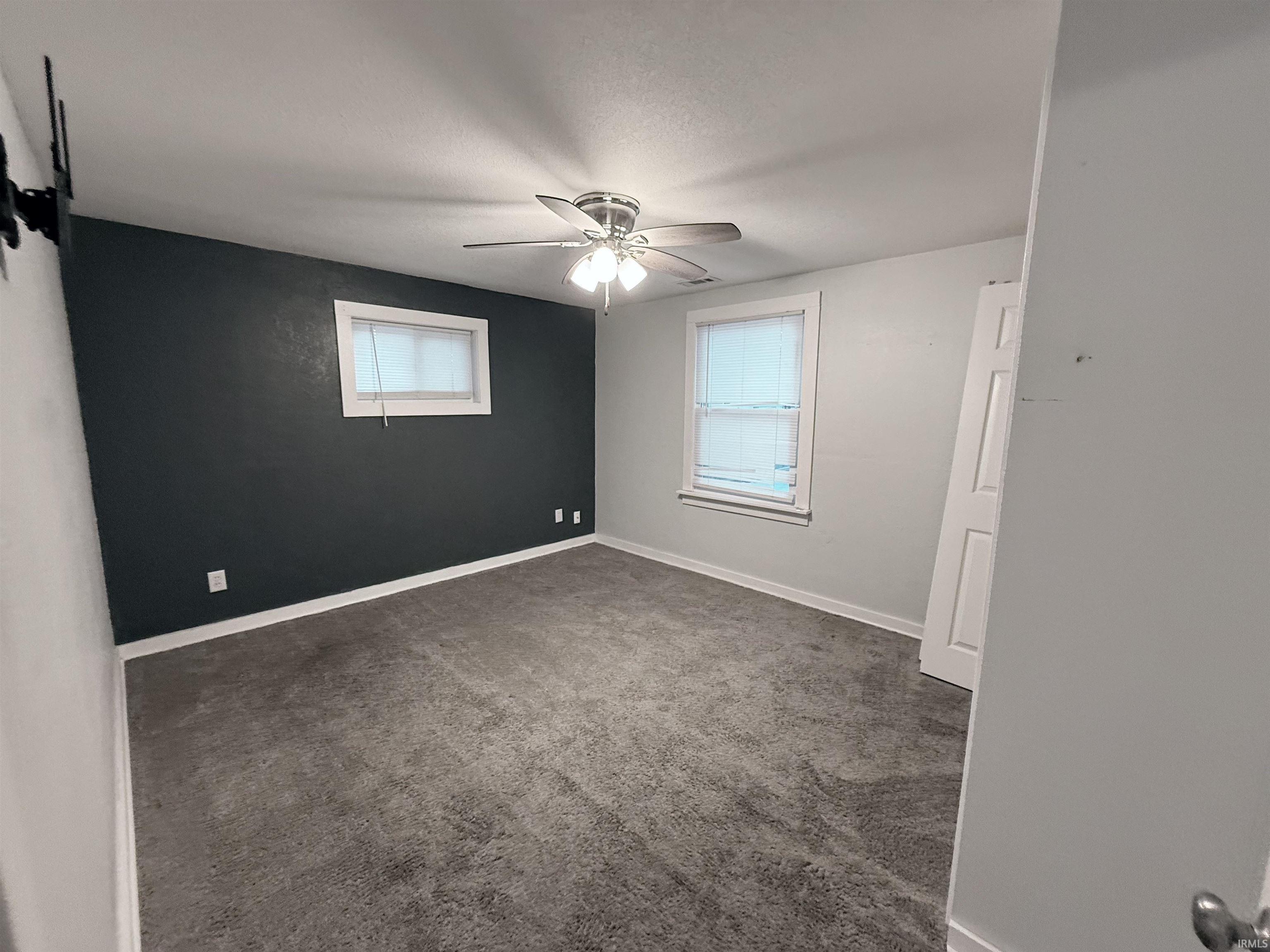 Spare room with dark carpet, healthy amount of natural light, and ceiling fan