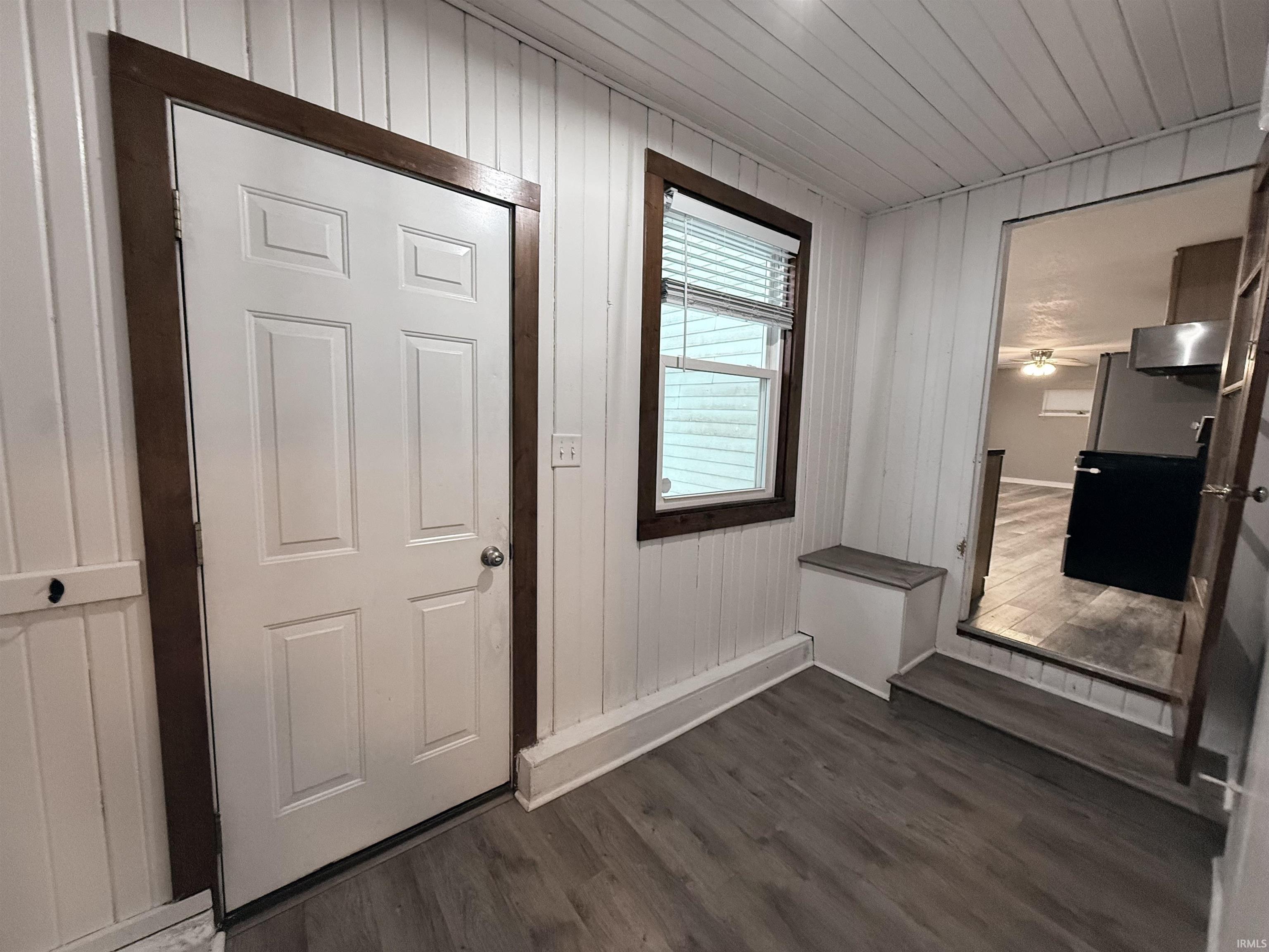 Entryway featuring wooden walls, dark wood finished floors, and wooden ceiling