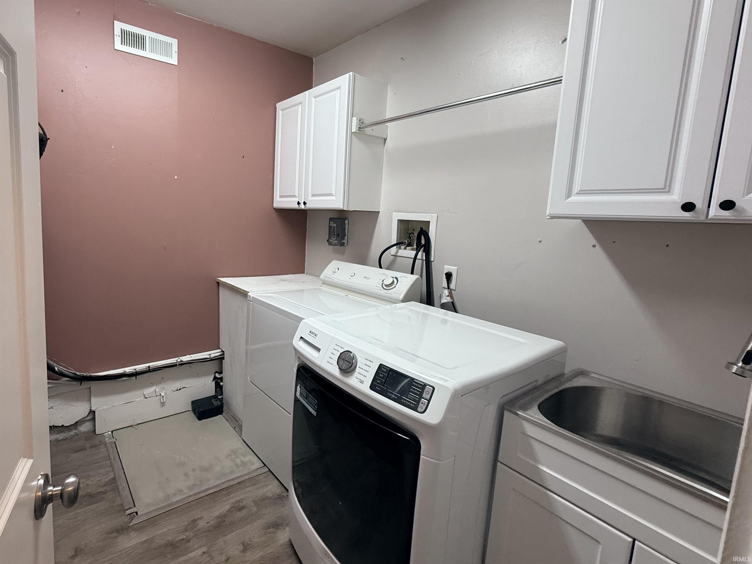 Laundry area featuring cabinet space, wood finished floors, and washing machine and clothes dryer