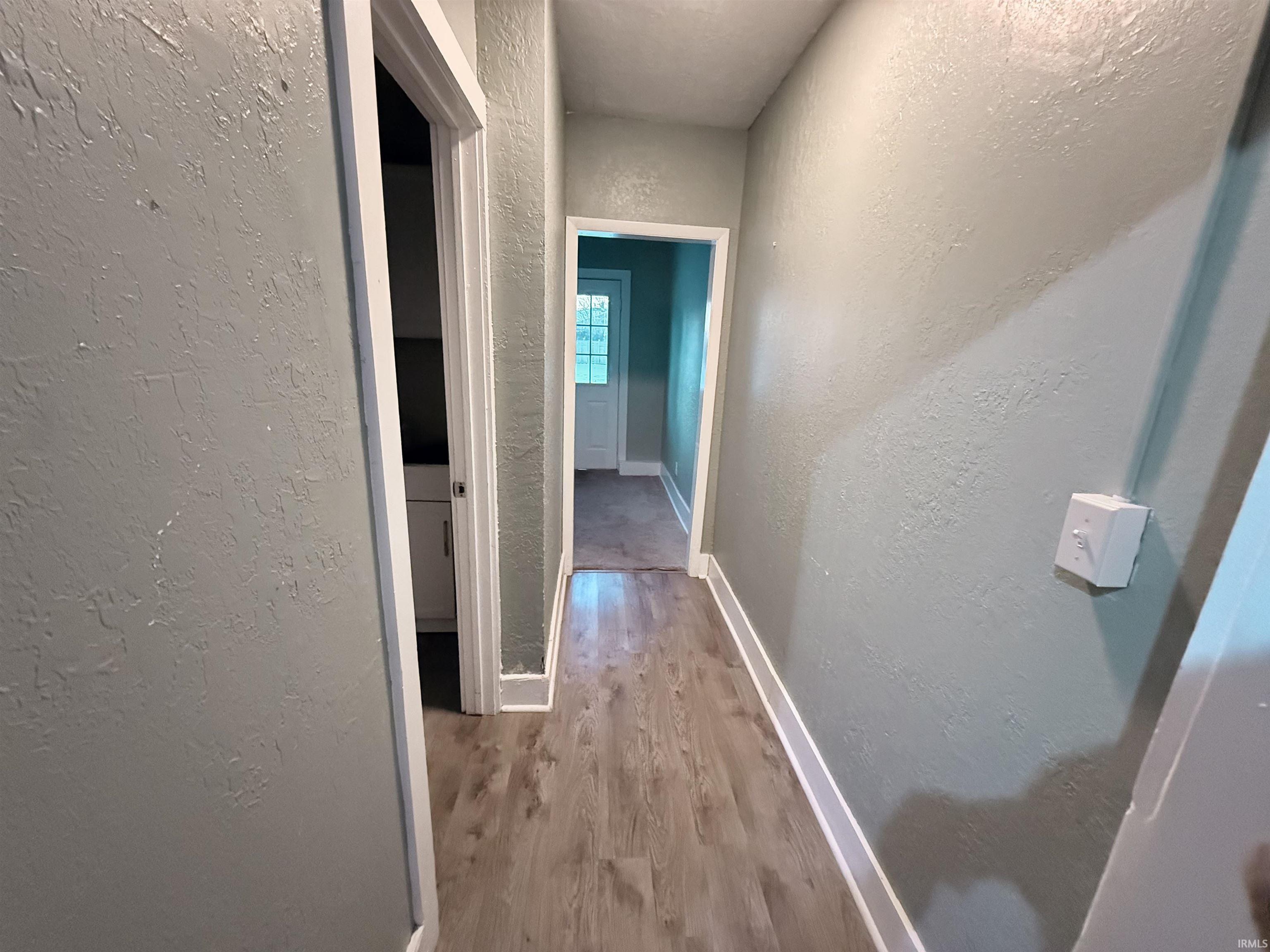 Corridor with a textured wall and light wood finished floors