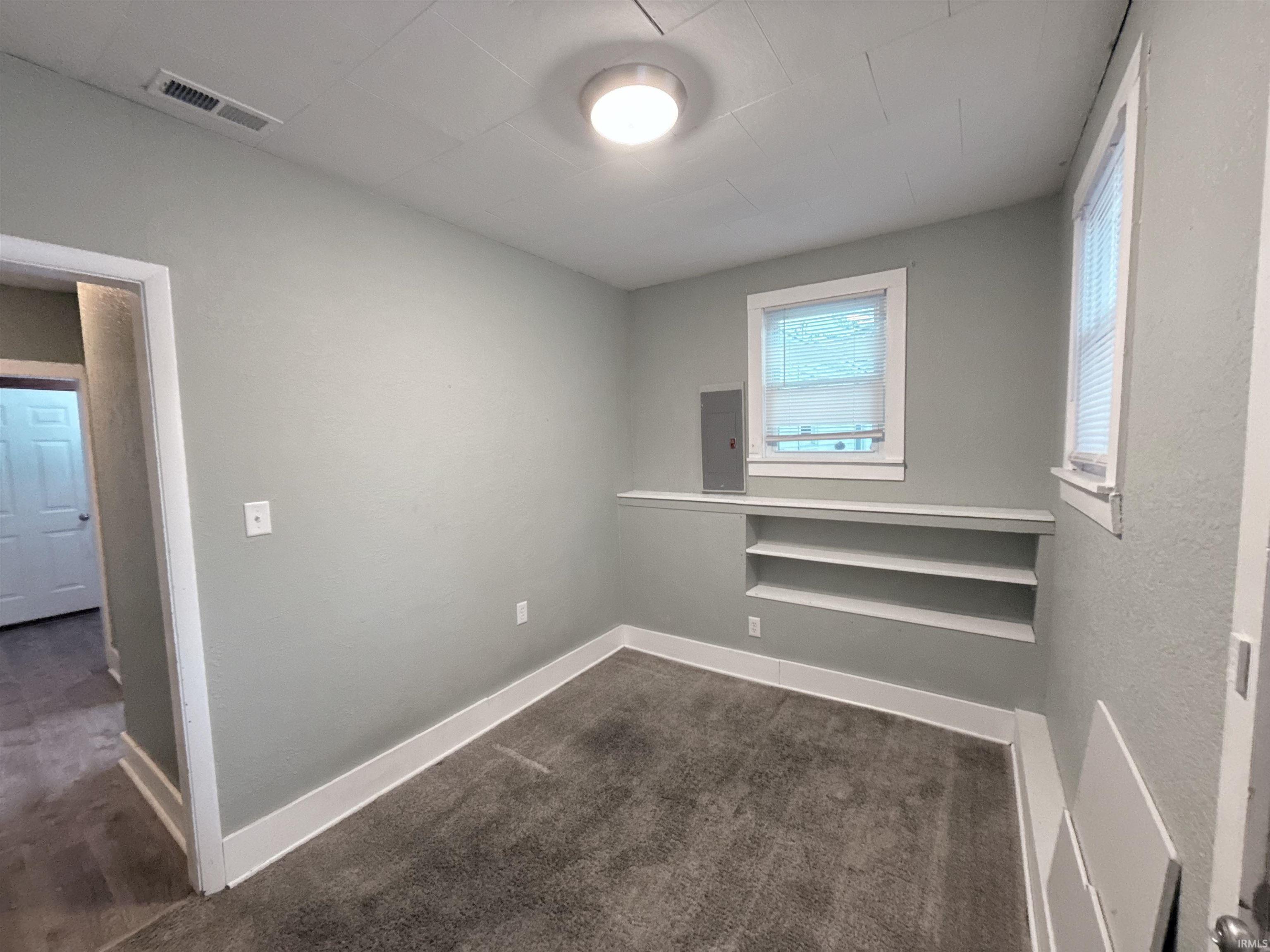 Unfurnished room with electric panel and dark carpet