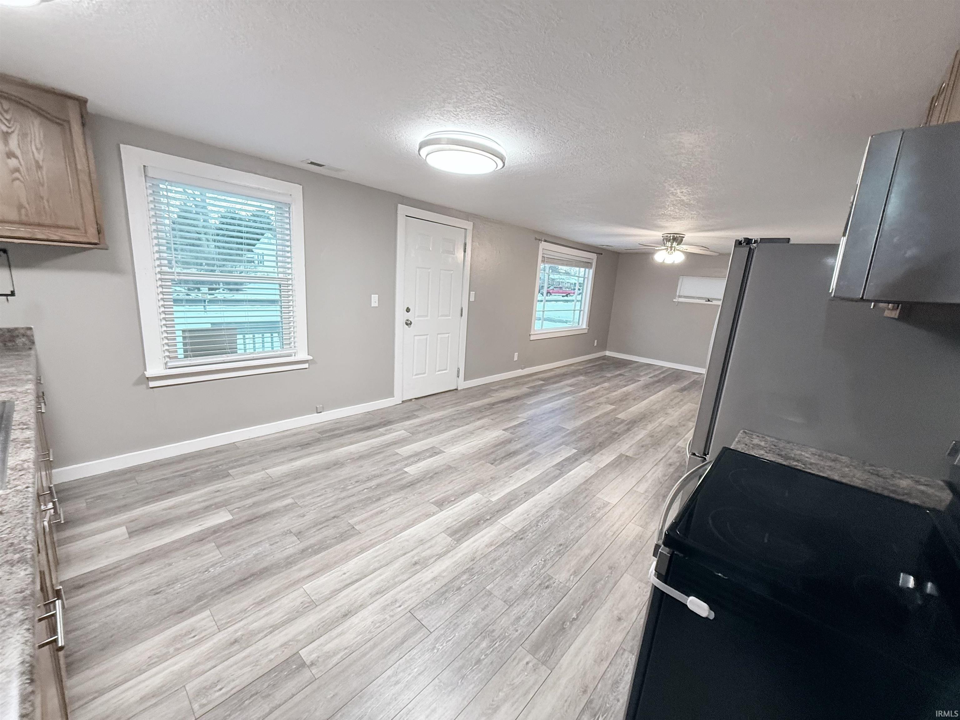 Unfurnished living room featuring a textured ceiling, light wood-style floors, and a ceiling fan